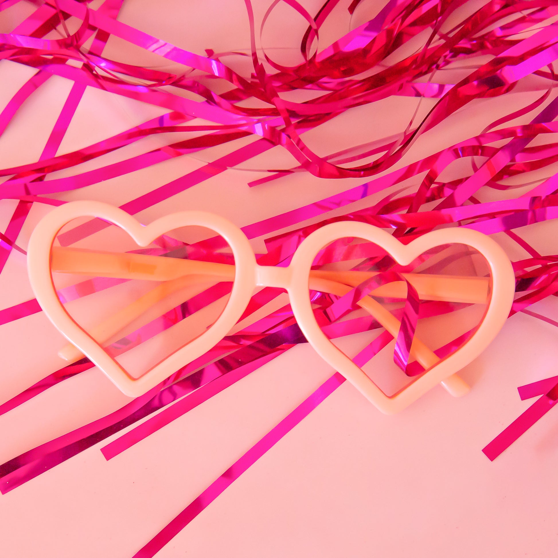 A pair of apricot colored heart shaped sunglasses. 