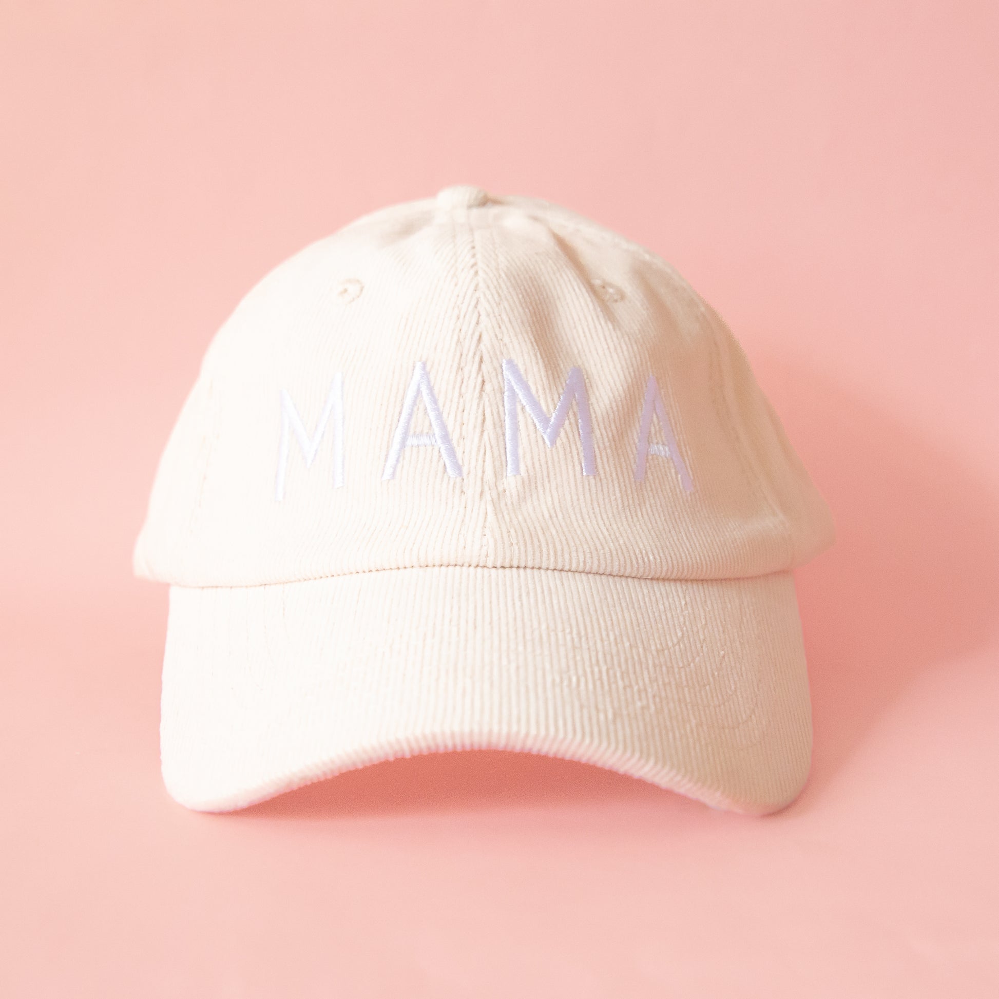 An ivory colored corduroy baseball hat with embroidered lettering that reads, "MAMA" in white across the front.