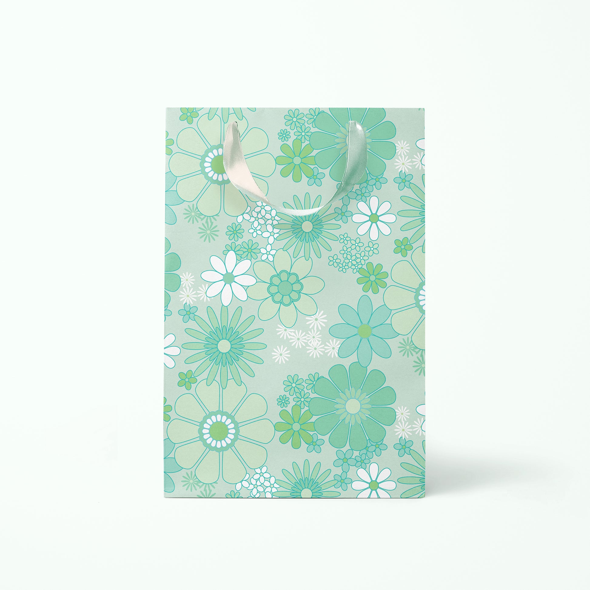 On a white background is a rendering of the medium gift bag with a mint and white floral print and ribbon handles.