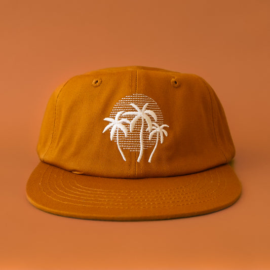 A burnt orange flat brim hat with a white embroidered palm logo. 