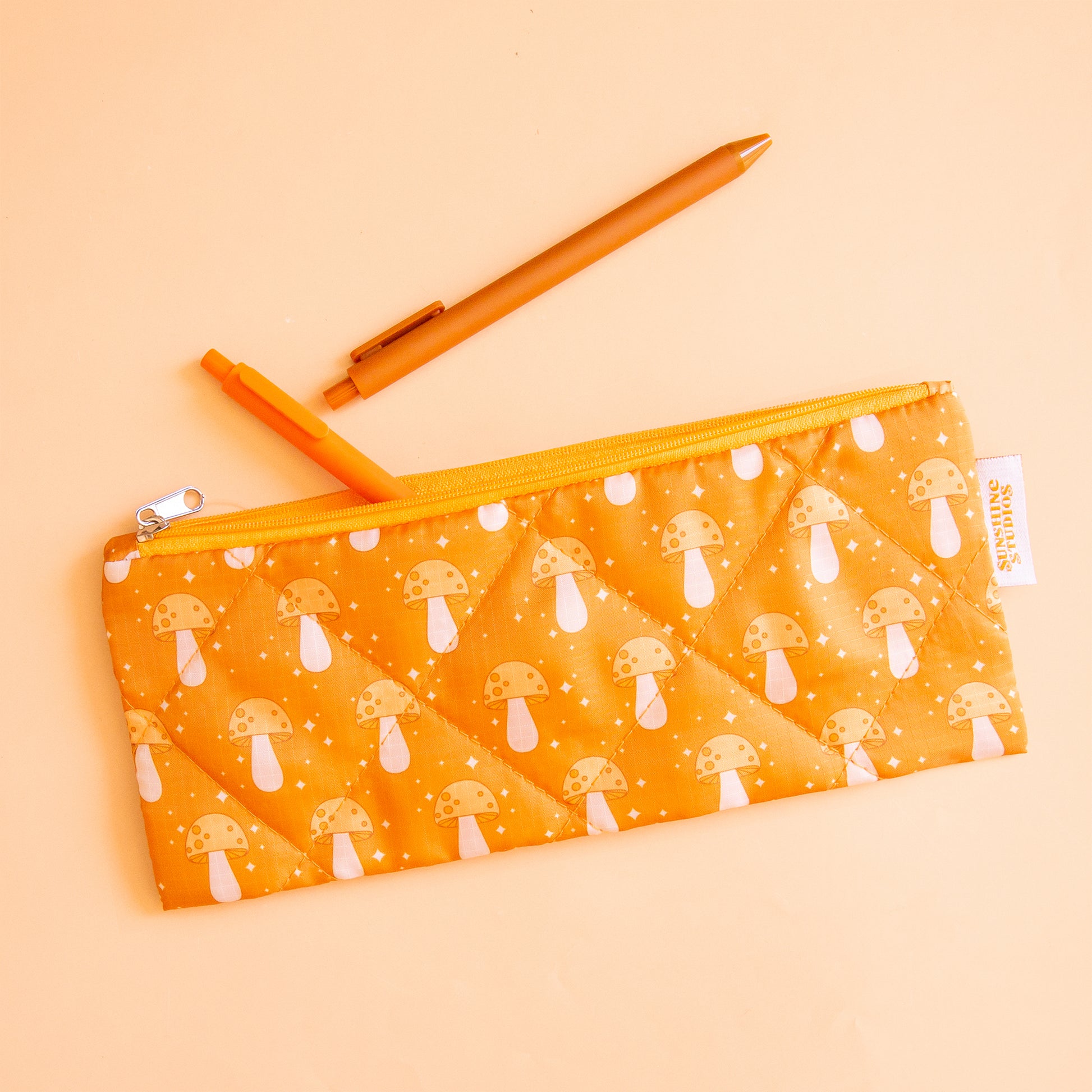 An orange pencil pouch with a mushroom print. 