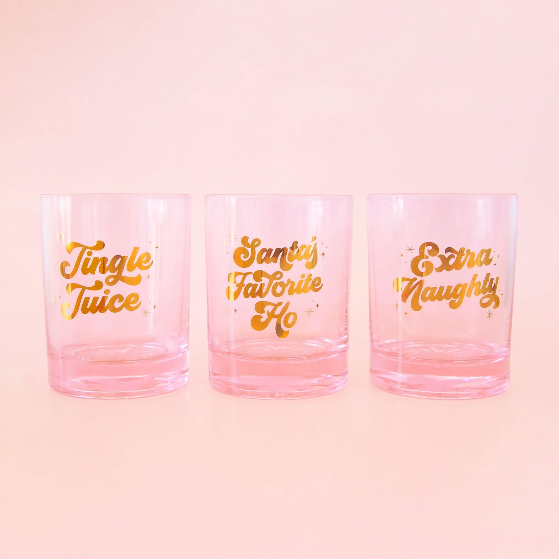 All three pink glass tumblers. One reads, "Jingle Juice", "Santa's Favorite Ho", "Extra Naughty". 
