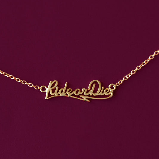 A gold nameplate style necklace that reads, "Ride or Die".