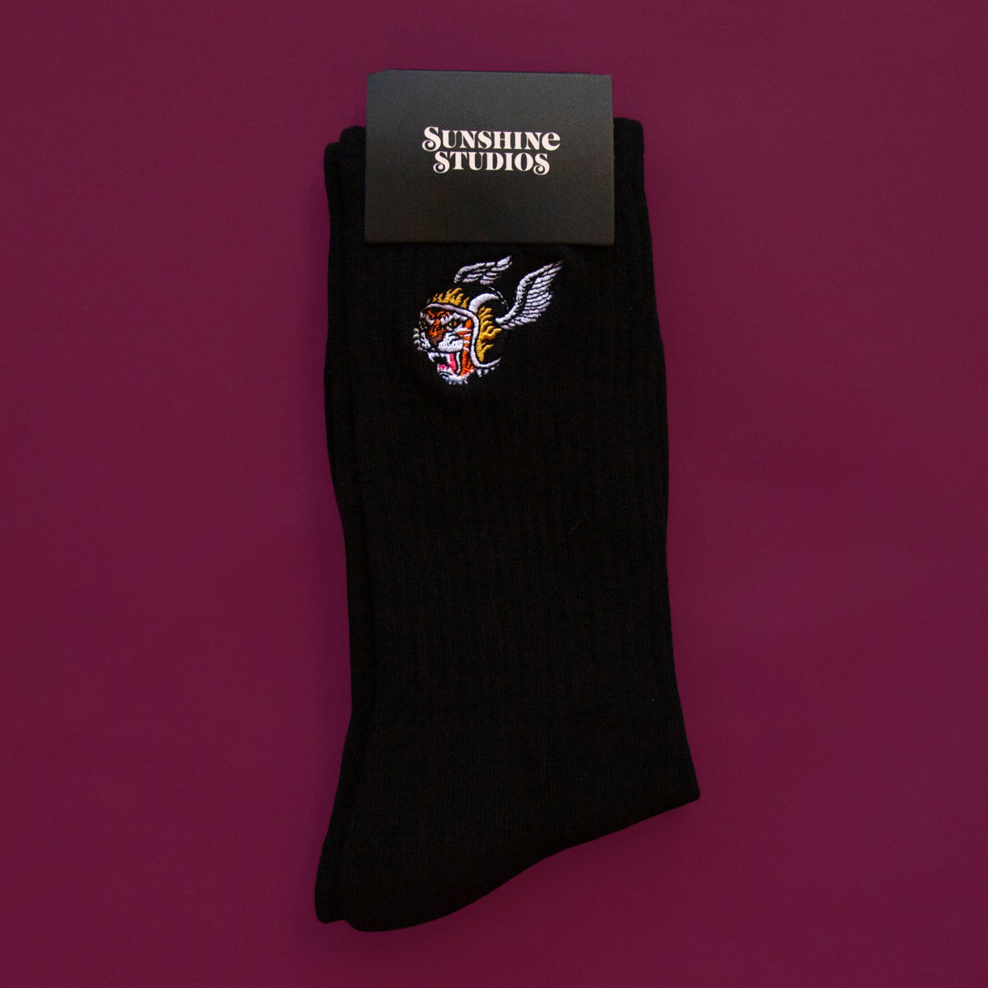 A black pair of crew socks with a tiger with a wing helmet graphic on the side. 