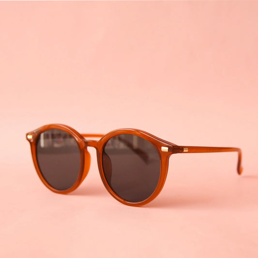 A thin rounded burnt orange / brown framed sunglass with a grey lens.