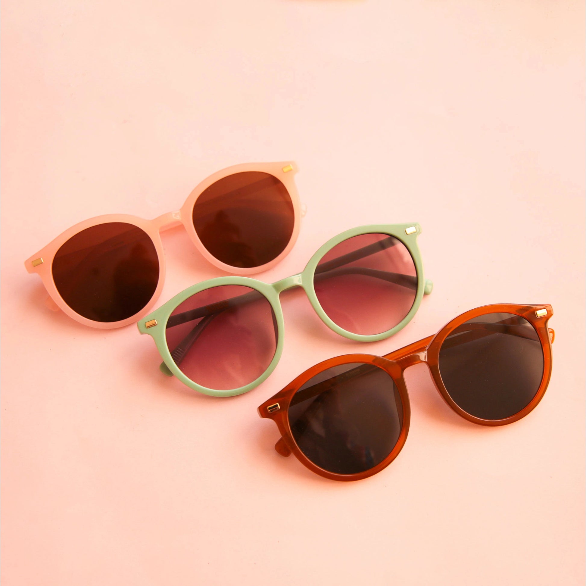 On a peach background is the three Sam sunglasses in the three color ways.