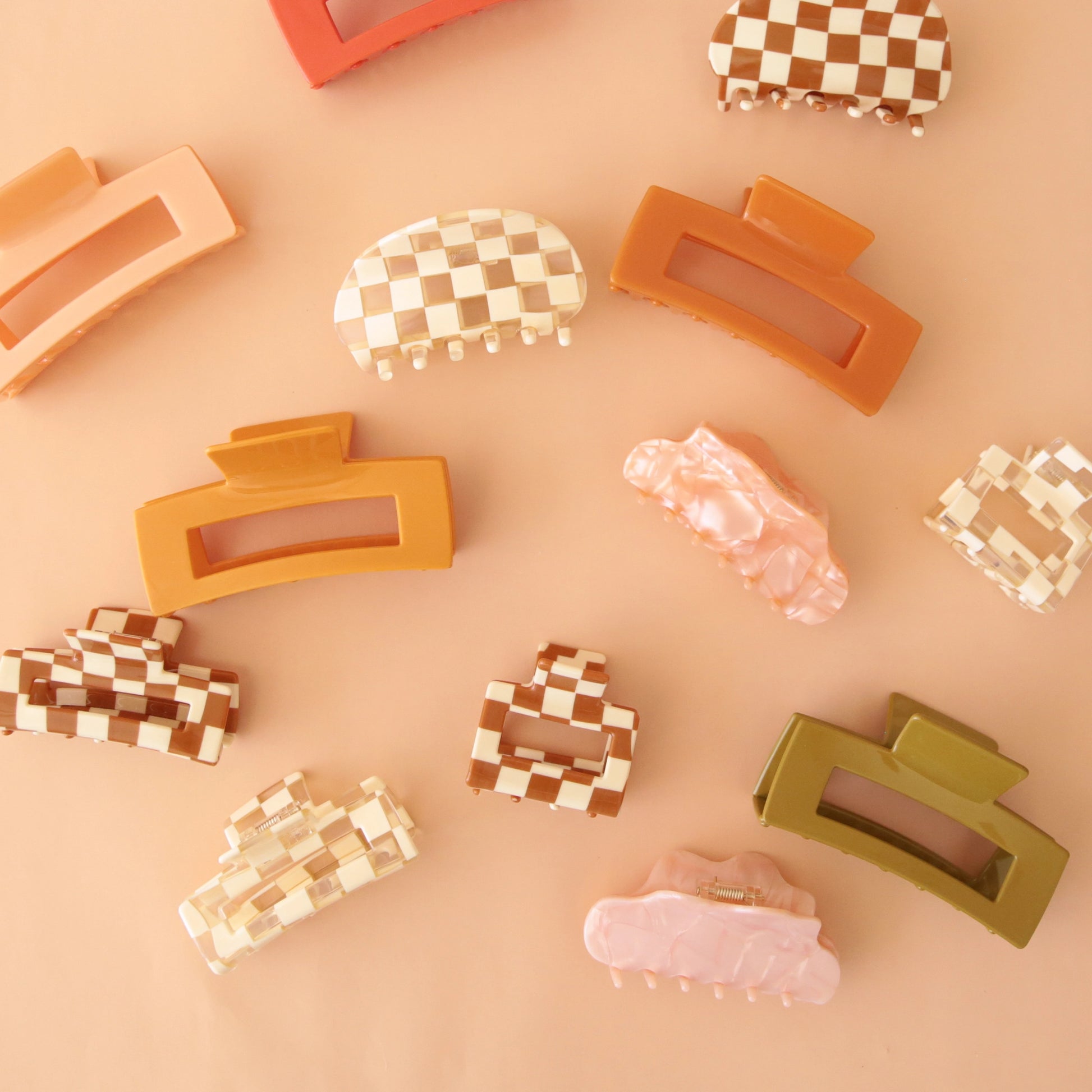 On a peachy background is an assortment of claw clips in different shapes and sizes.