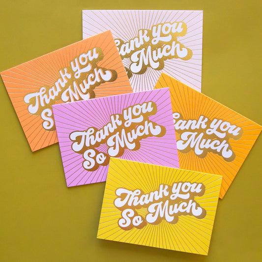 On a green background is a pack of 5 thank you cards in a variety of colors that all read, "Thank You So Much" in white letters and gold foiled outlined.