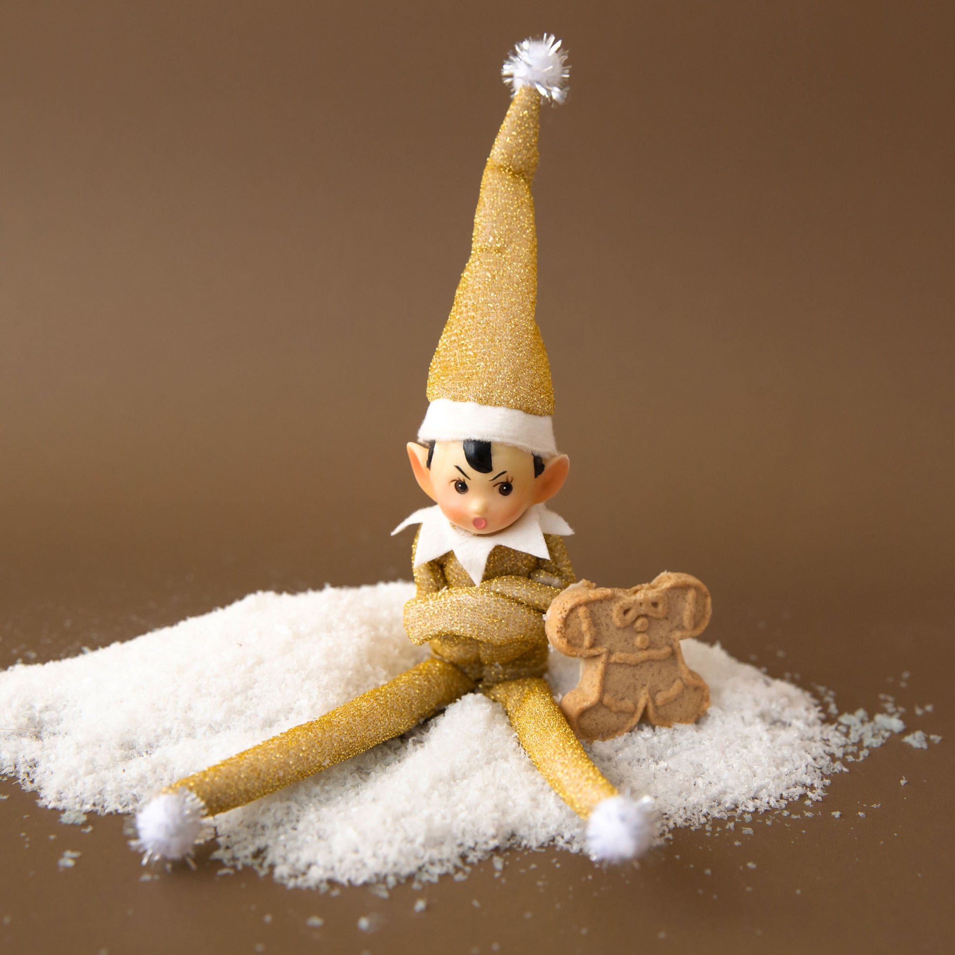 A gold sparkle elf shaped ornament with long limbs. 