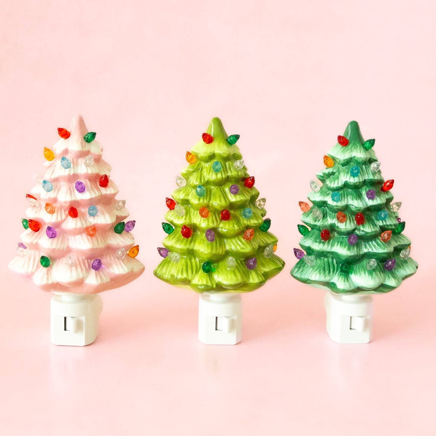 Three ceramic christmas tree shaped night lights.  The night light has multi colored lights all over it and the ceramic comes in three different colors - Pink, Light Green and Dark Green. 
