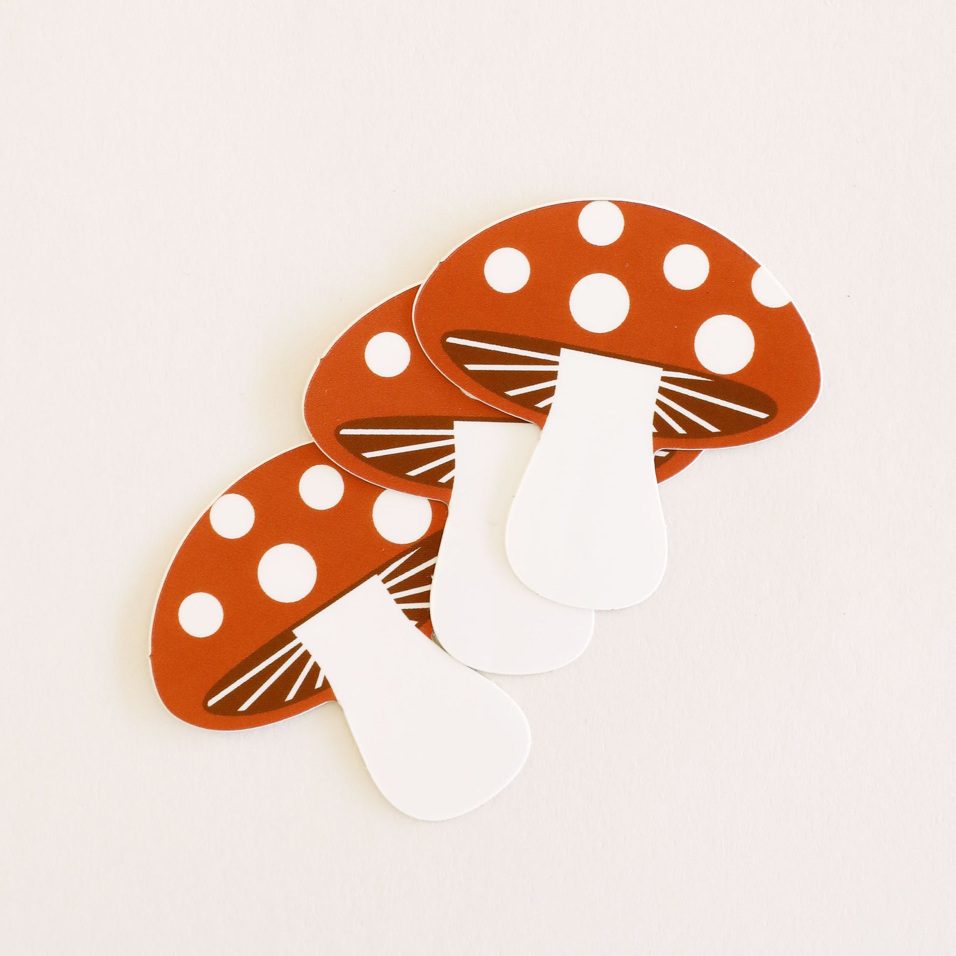 Three classic mushroom stickers with curved red tops with white polk-a-dots and white stems.