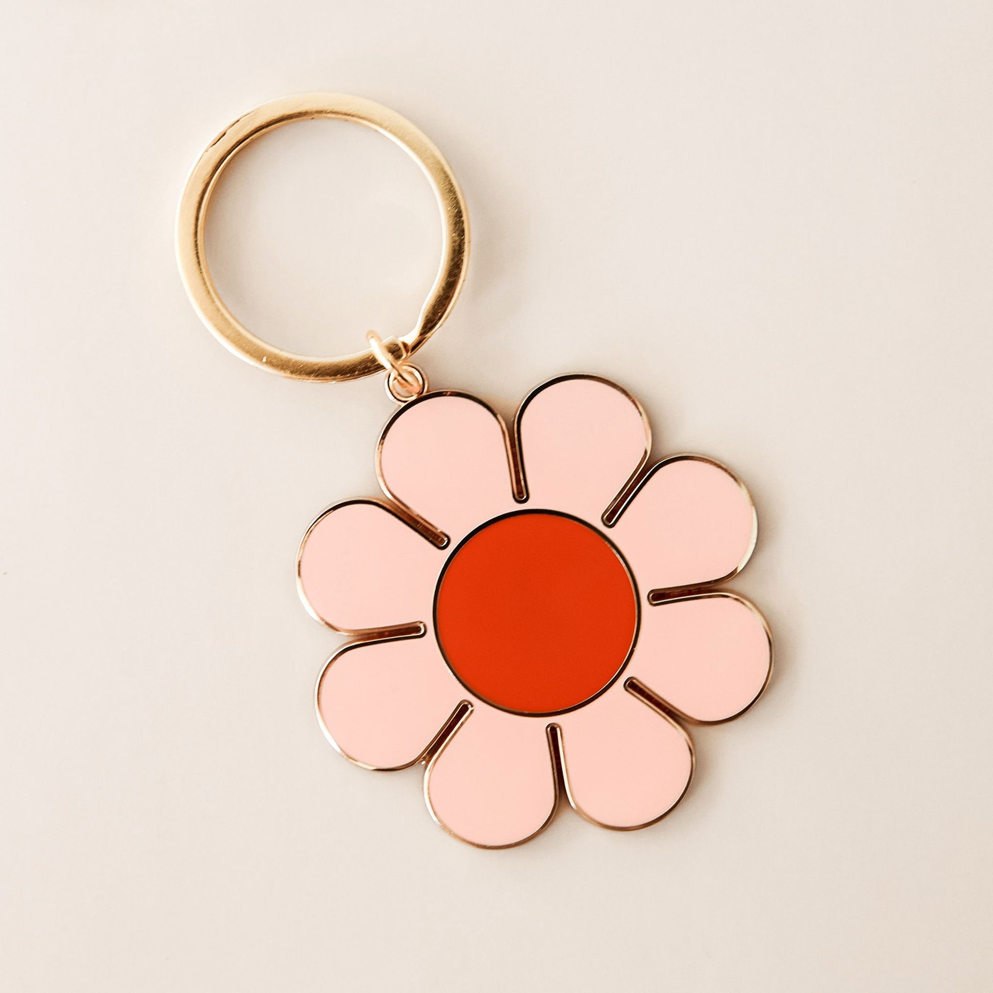  Light pink daisy keychain on a gold ring with a red center.