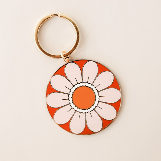 Circle flower keychain with light beige petals and orange center. The keychain is complete with a golden key chain ring.