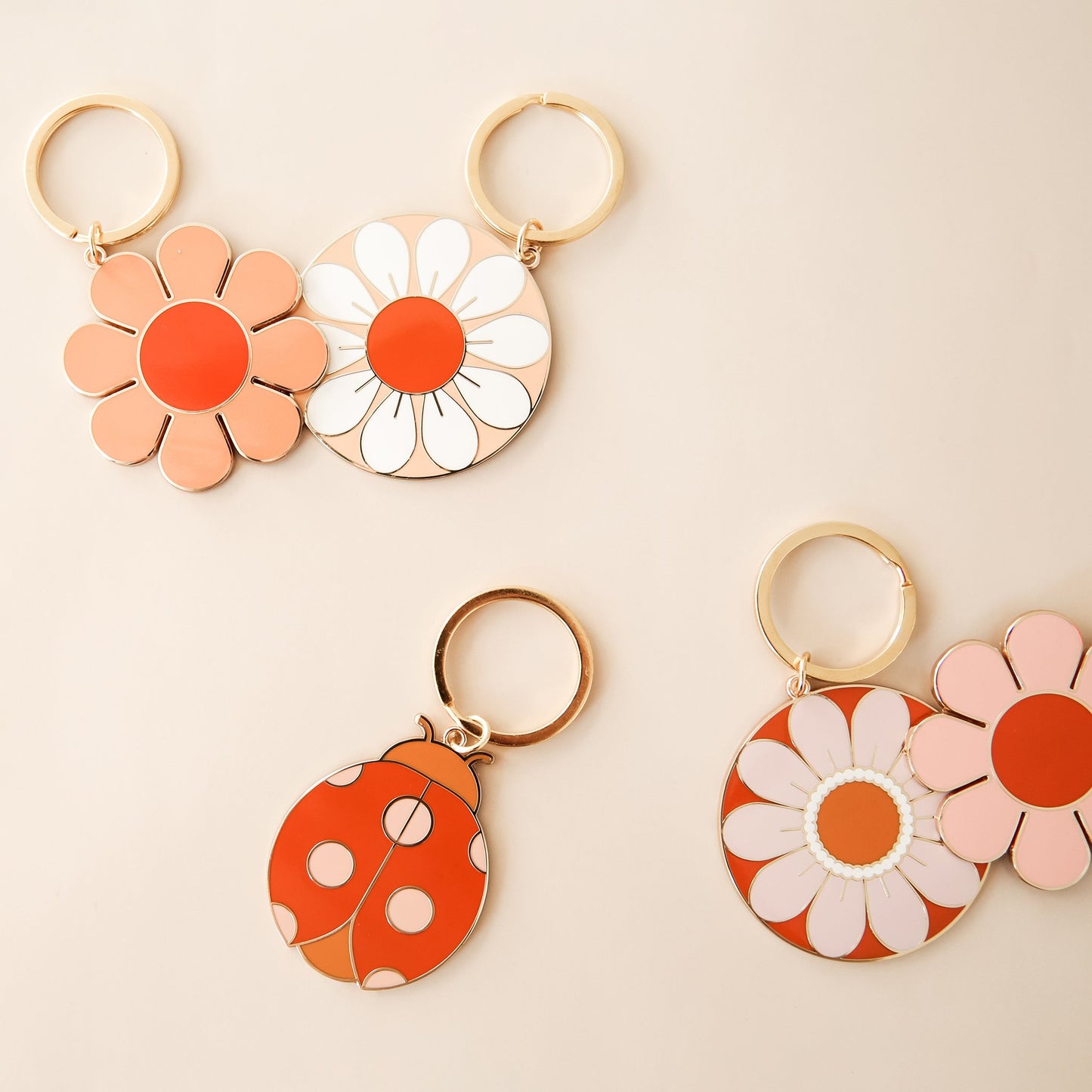 Five key chains, including a variety of warm toned flowers and a lady bug. Each keychain is complete with a golden key chain hoop.