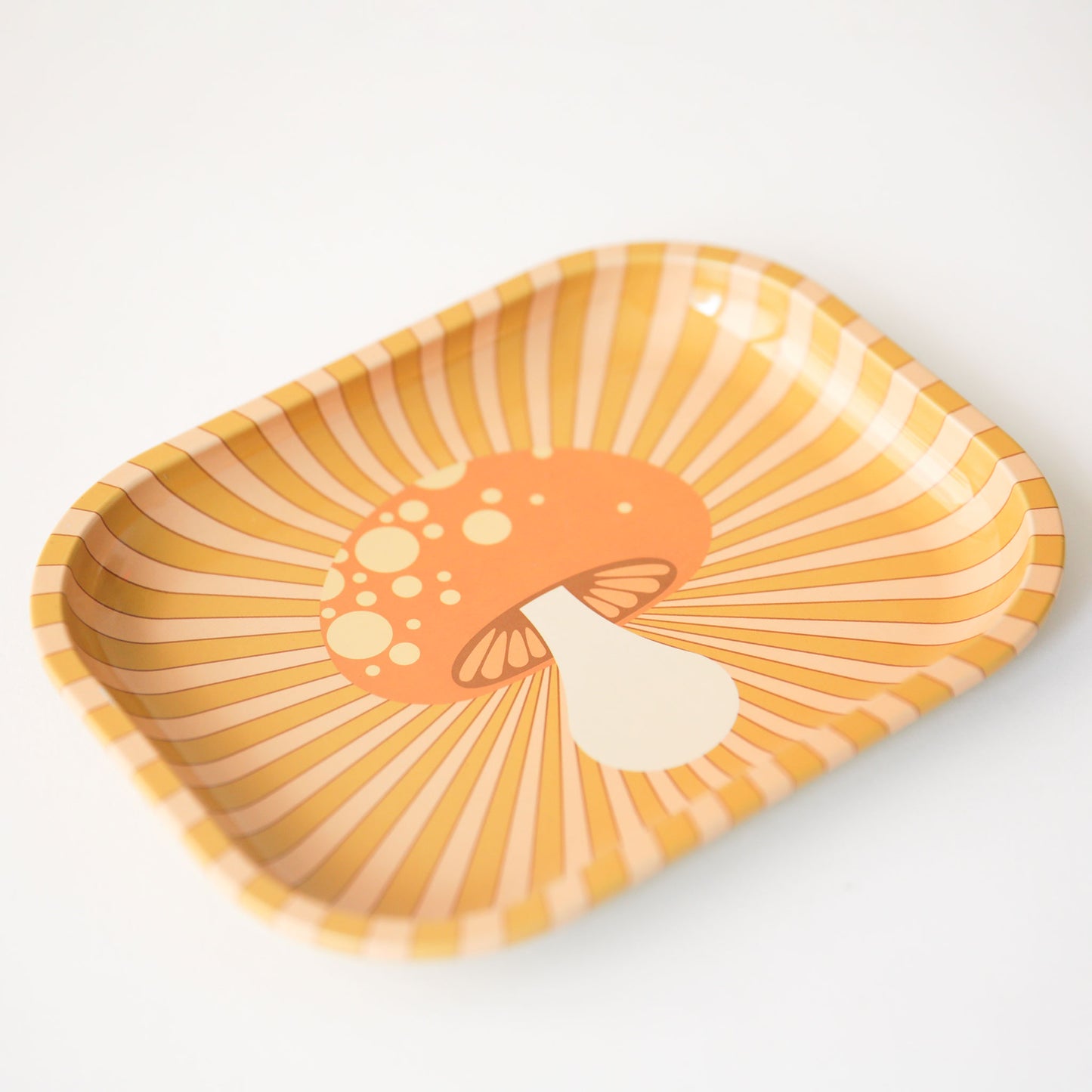 An orange and light pink metal tray with a groovy mushroom graphic in the center.