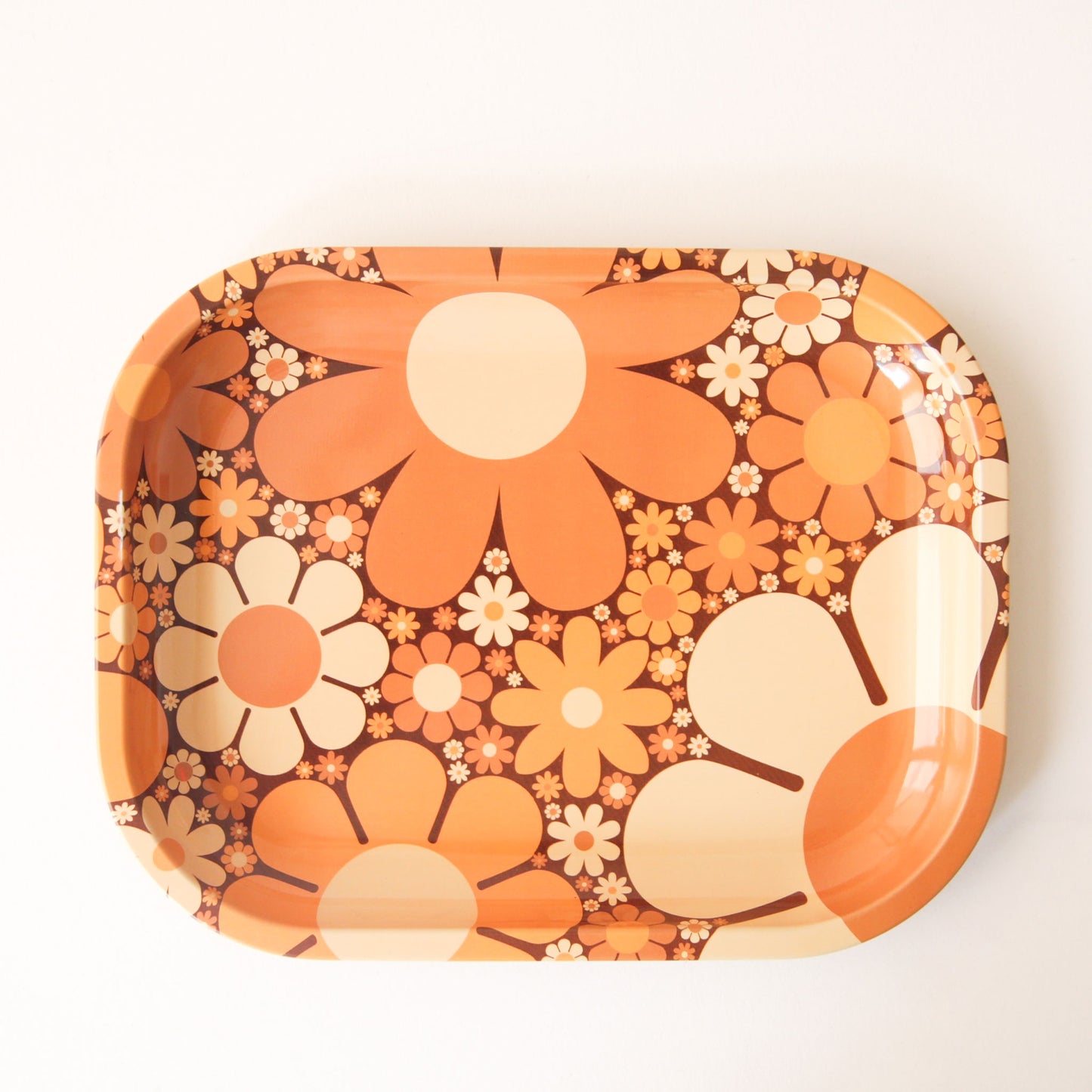 A metal tray perfect for rolling or all your favorite trinkets. It features a 70's inspired floral design with a variation of daisies in different shapes, sizes and colors.