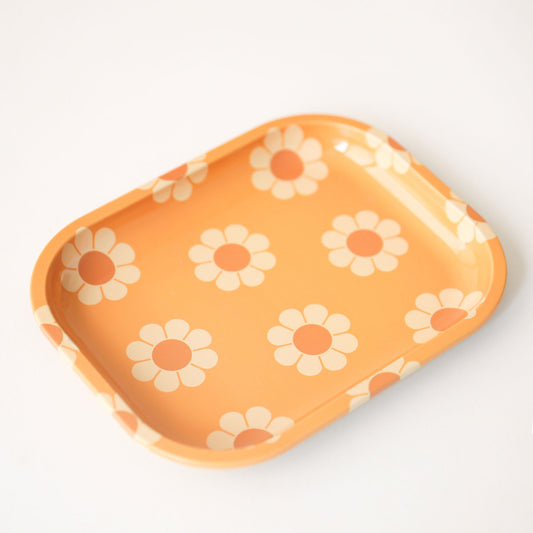 An orange metal tray perfect for rolling or all your trinkets. The groovy tray features a vintage inspired daisy design.