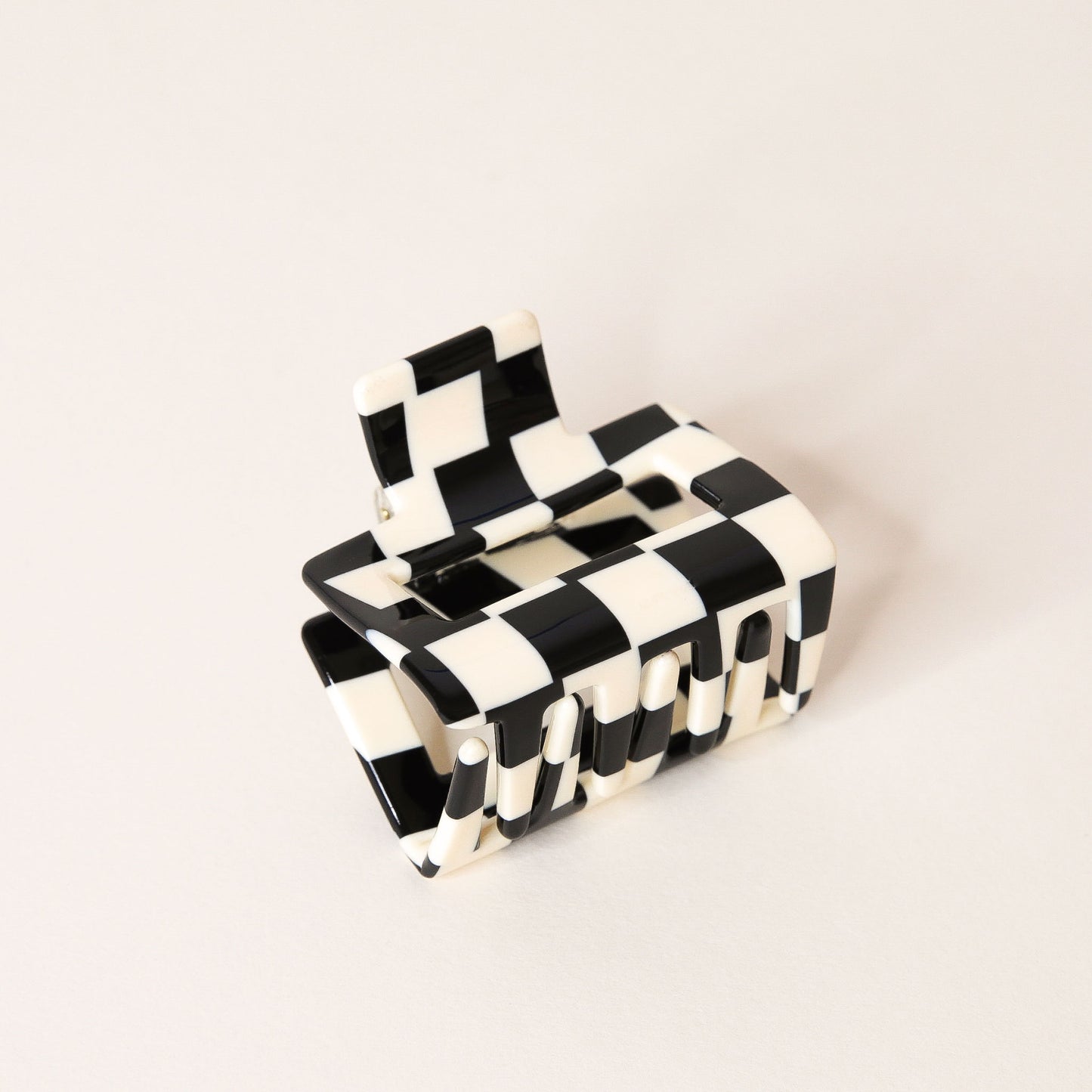 Small black and white checkered claw hair clip with a square shape and two simple geometric cutouts.