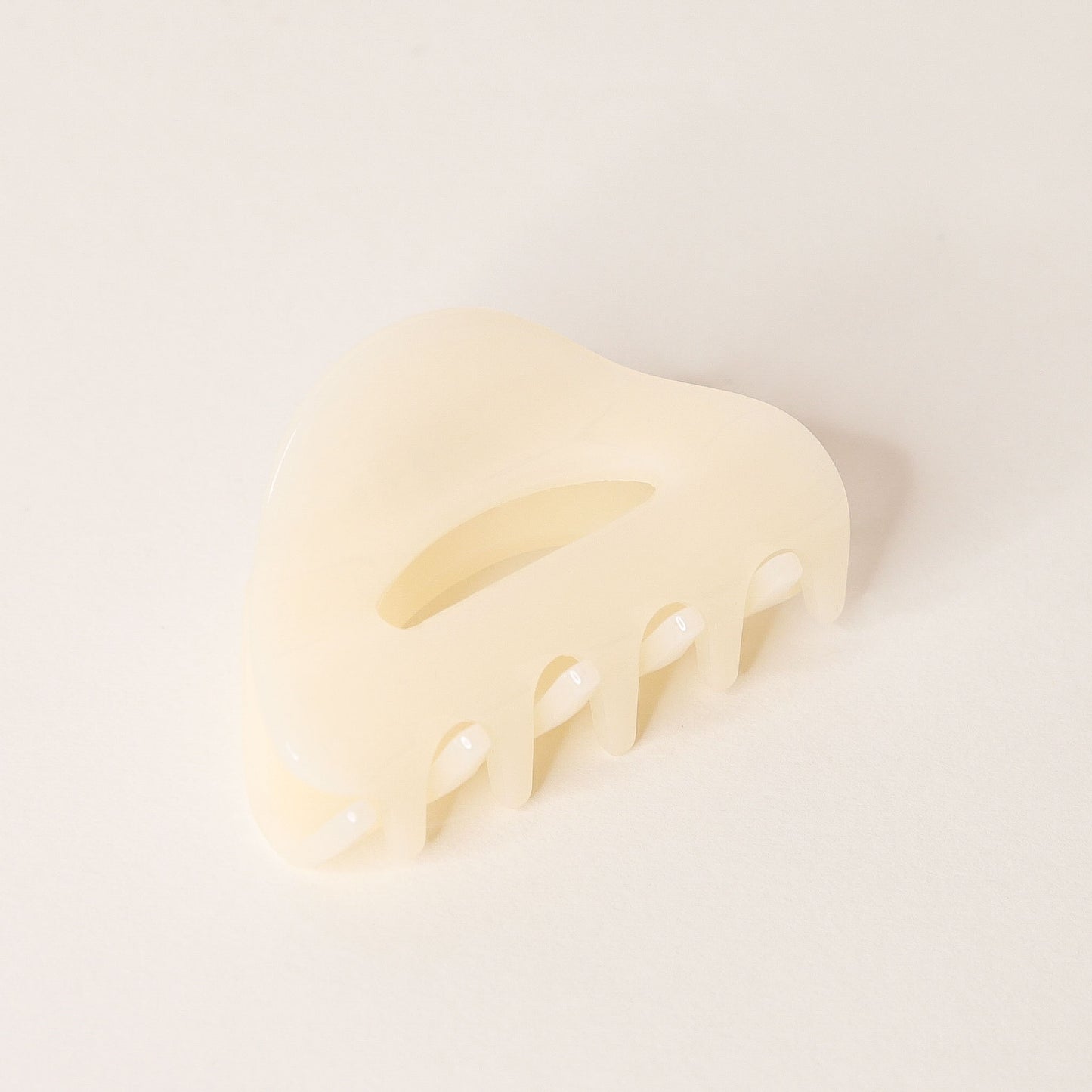 Cream claw hair clip with rounded edges and two simple oval cutouts.
