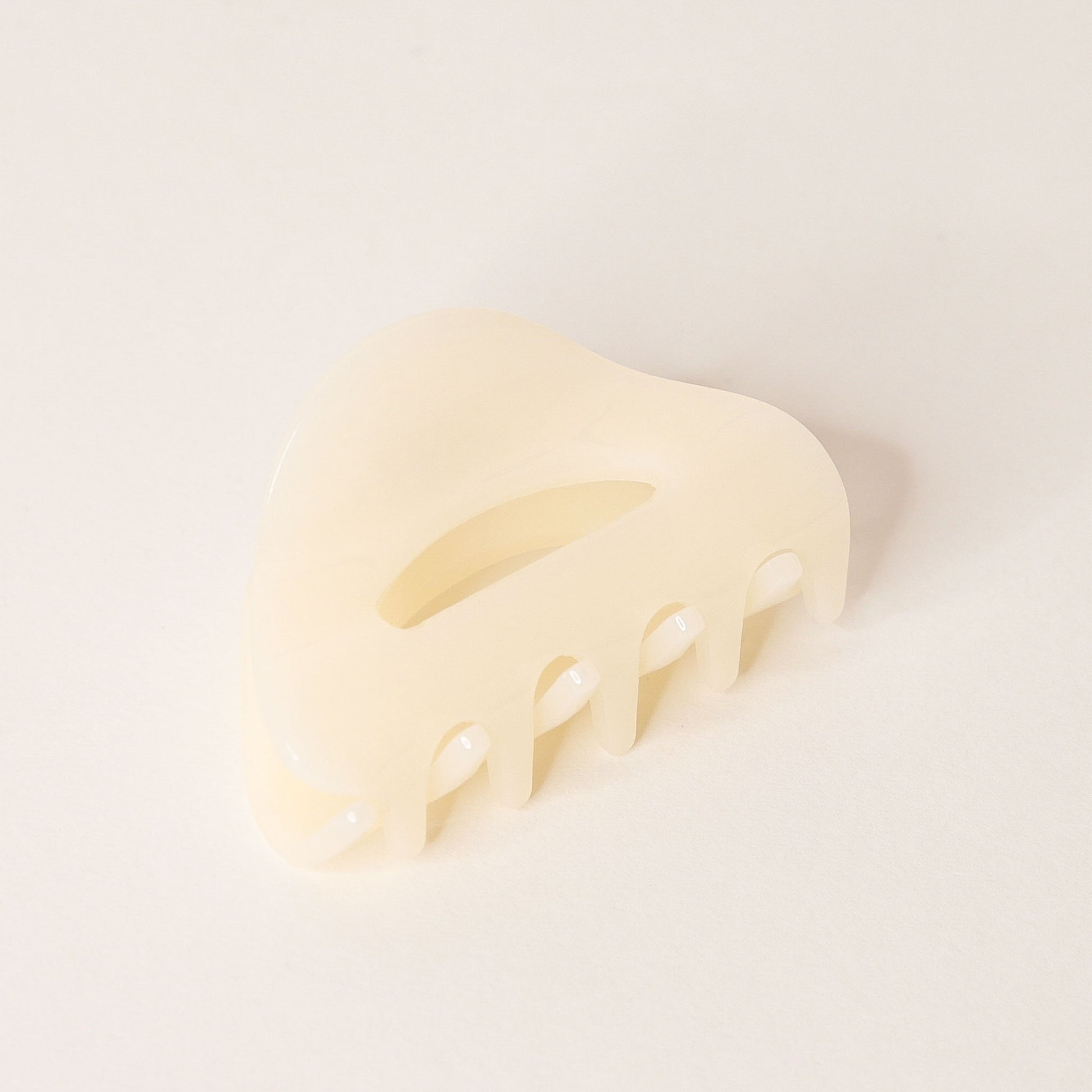 Cream claw hair clip with rounded edges and two simple oval cutouts.