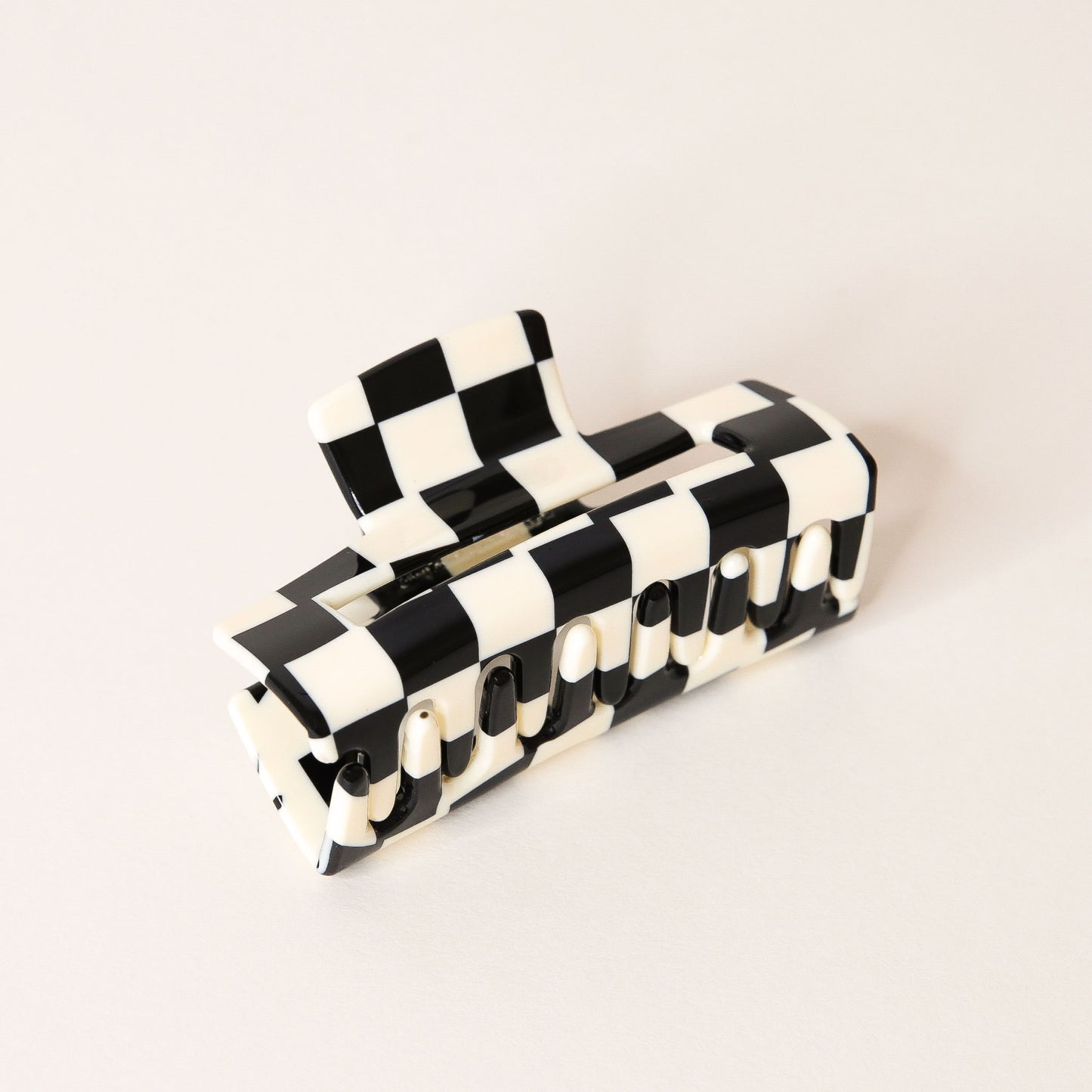 Large black and white checkered claw hair clip with a narrow rectangle shape and two simple geometric cutouts. 