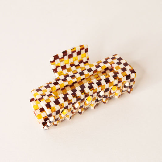 Large white and brown acrylic checkered claw hair clip with a narrow rectangle shape and two simple geometric cutouts.