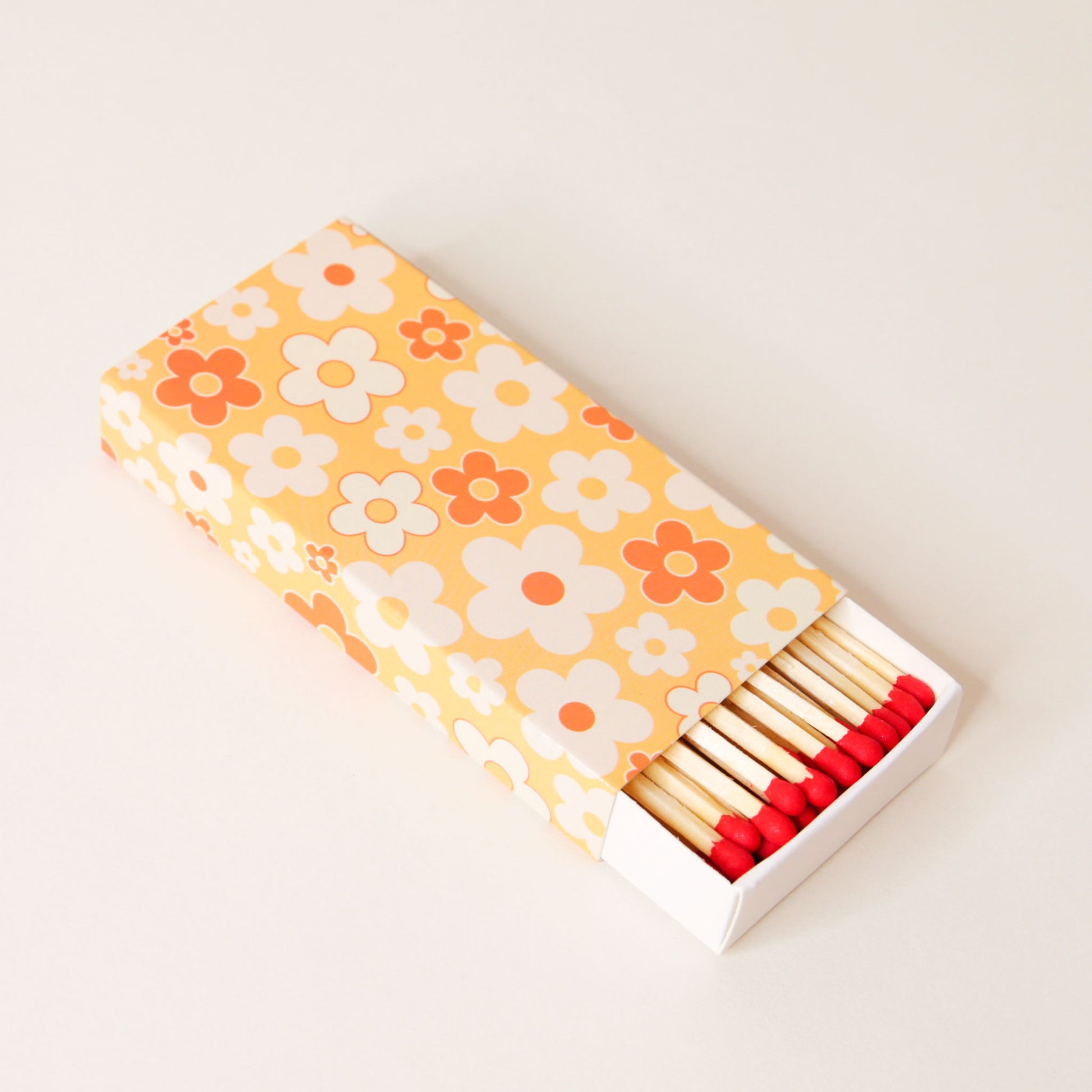 Rectangular match box positioned open, revealing a full carton of matches with red dipped tips.