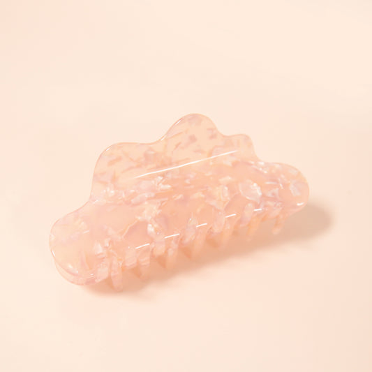 A claw clip featuring a wavy edge detail and along with specks of shine throughout the neutral rosy hair accessory.