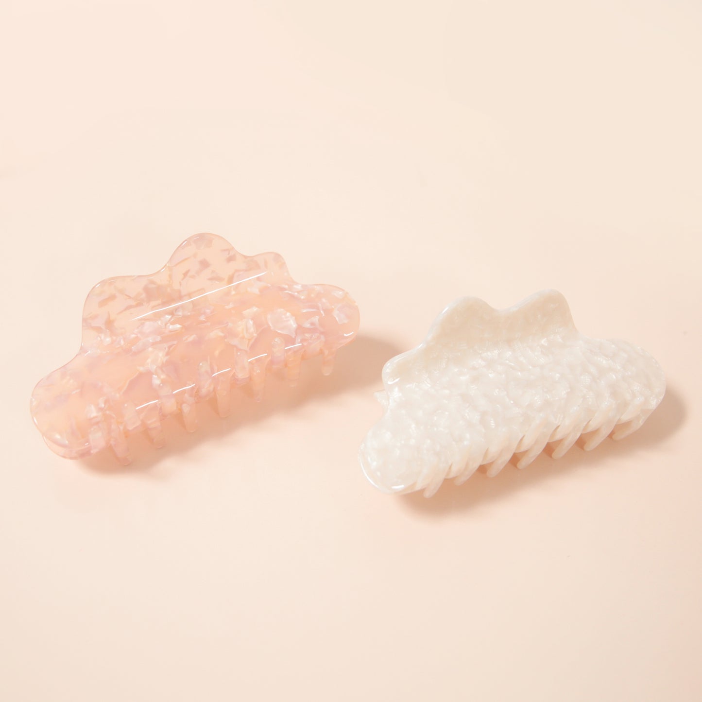 A claw clip featuring a wavy edge detail and along with specks of shine throughout the neutral rosy hair accessory