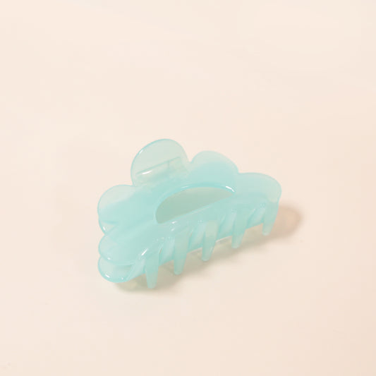 An aqua scalloped claw clip made of durable plastic.