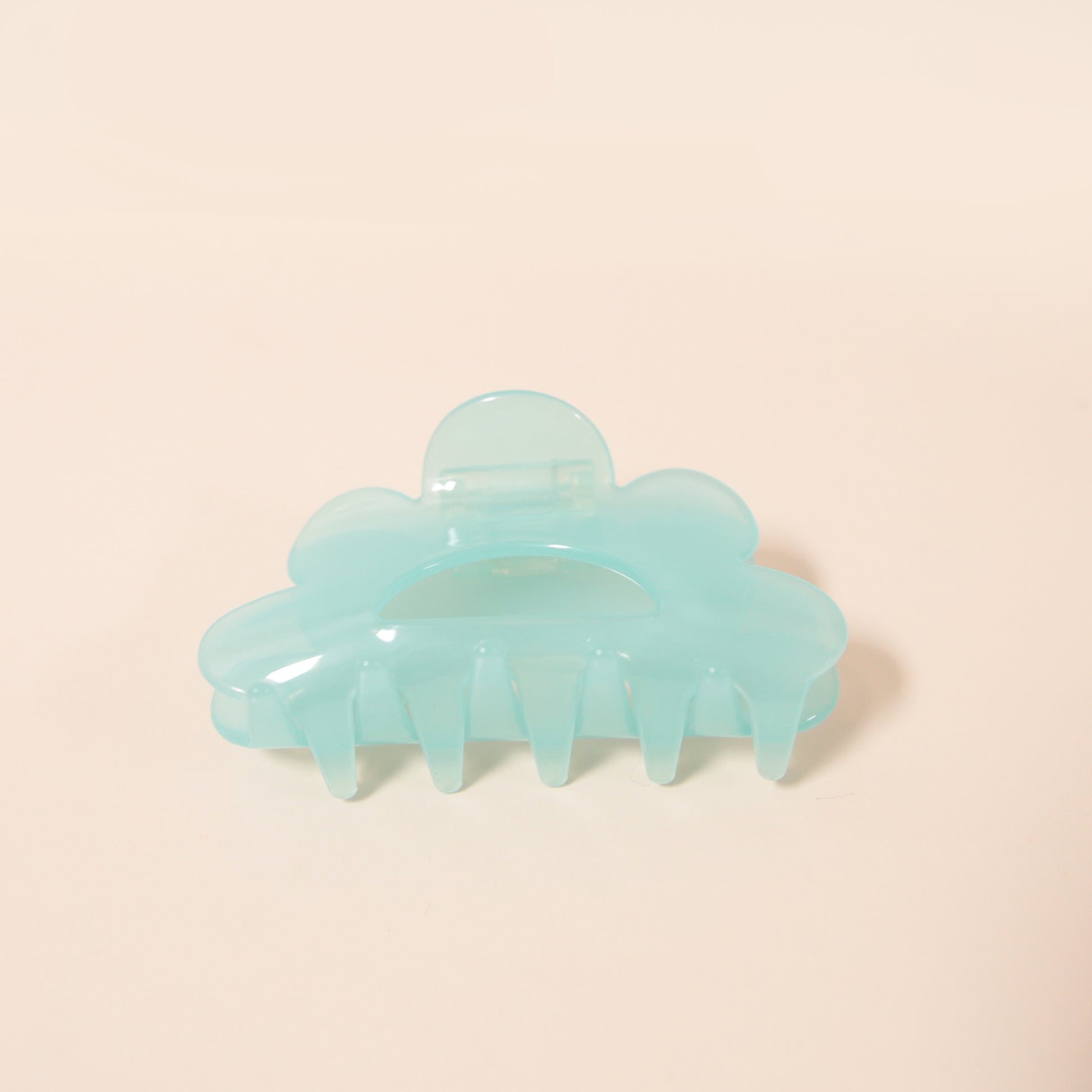 An aqua scalloped claw clip made of durable plastic.