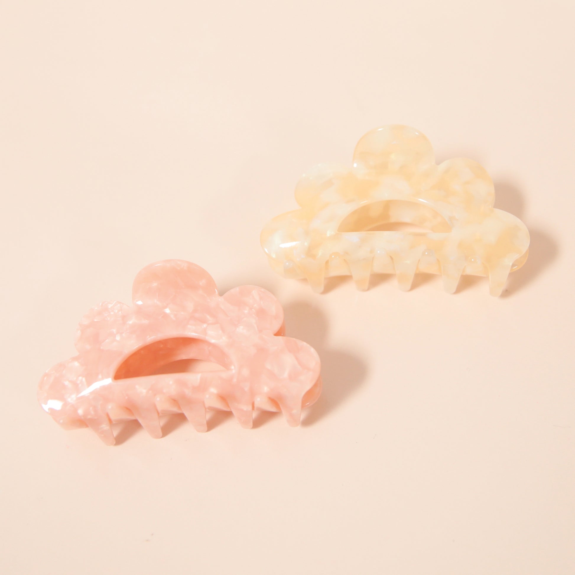 An ivory claw clip with a scalloped edge detail and an ivory and white color.