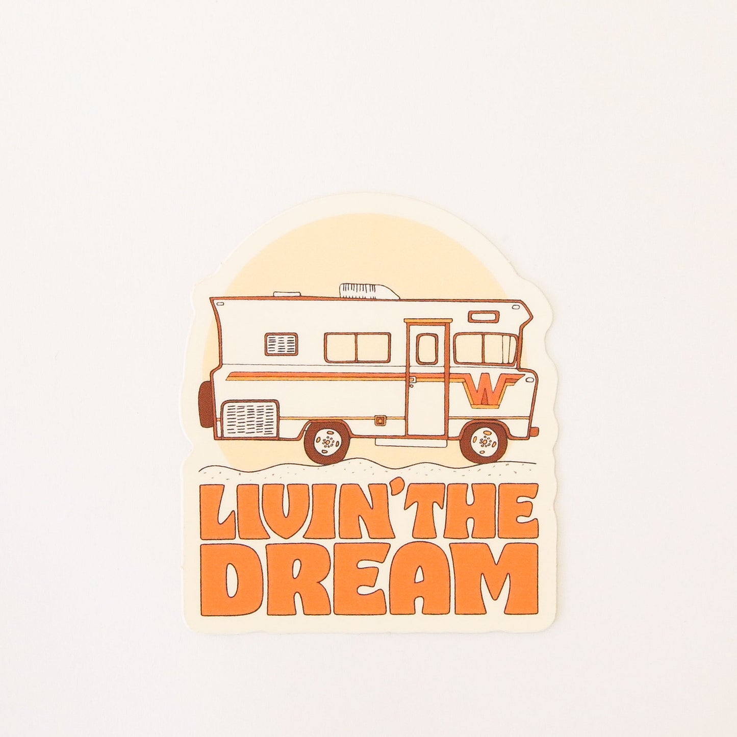 Retro inspired sticker featuring a old school RV camper with orange and yellow detailing. Below the van reads 'Livin' the dream' in orange capital bubble letters. 
