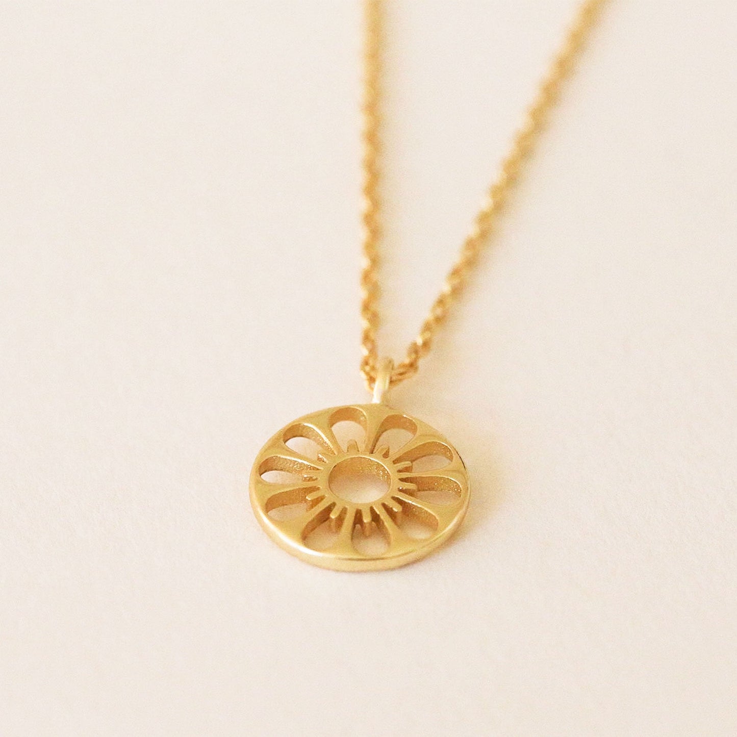 Gold chain necklace complete with circle pendant. The outline of a pleasant daisy is carved out of the pendent.