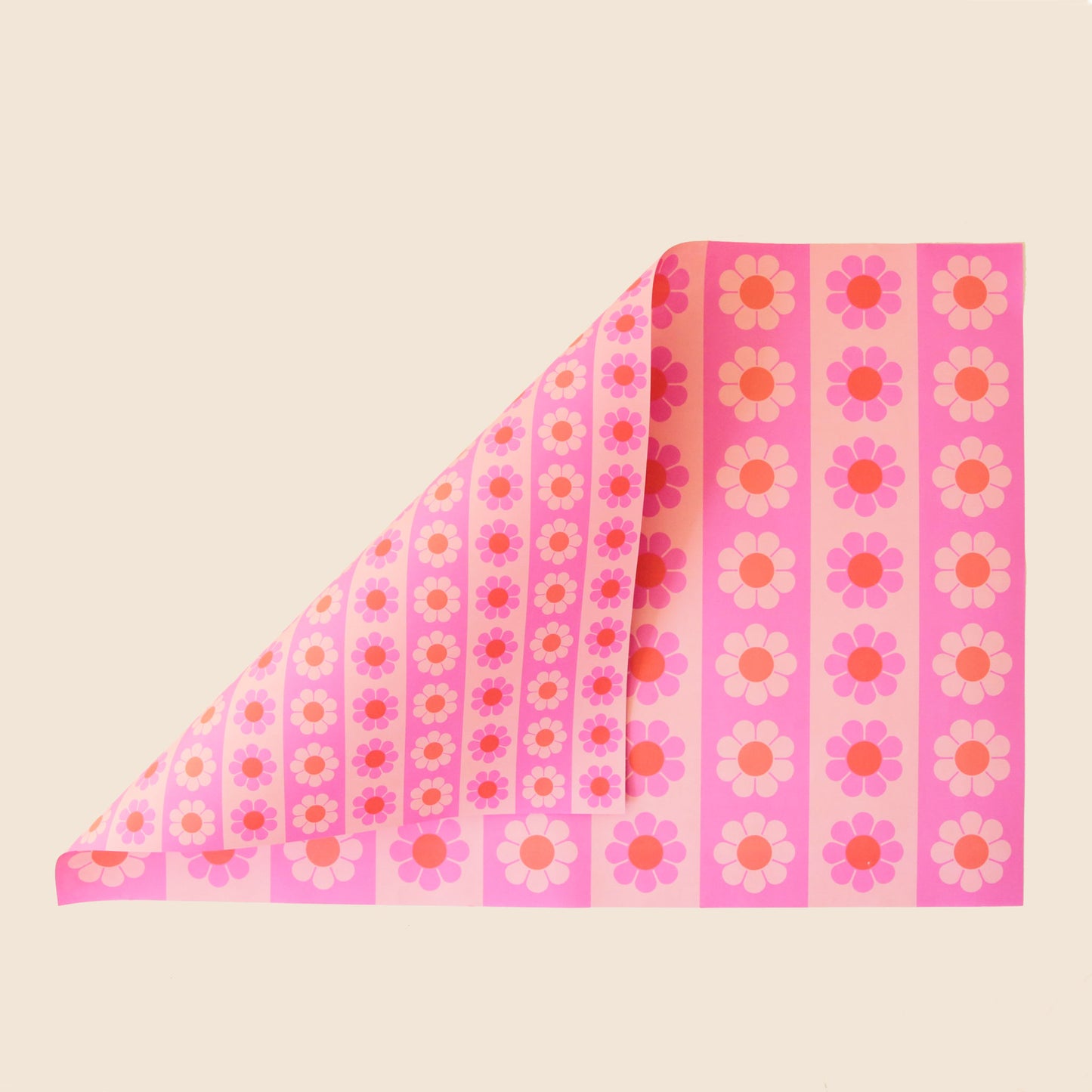 Sheet of wrapping paper filled with stripes of pink and orange flowers. The sheet is bent forward, revealing the other side of the wrapping paper. The back side is covered in thinner stripes of the same floral print.