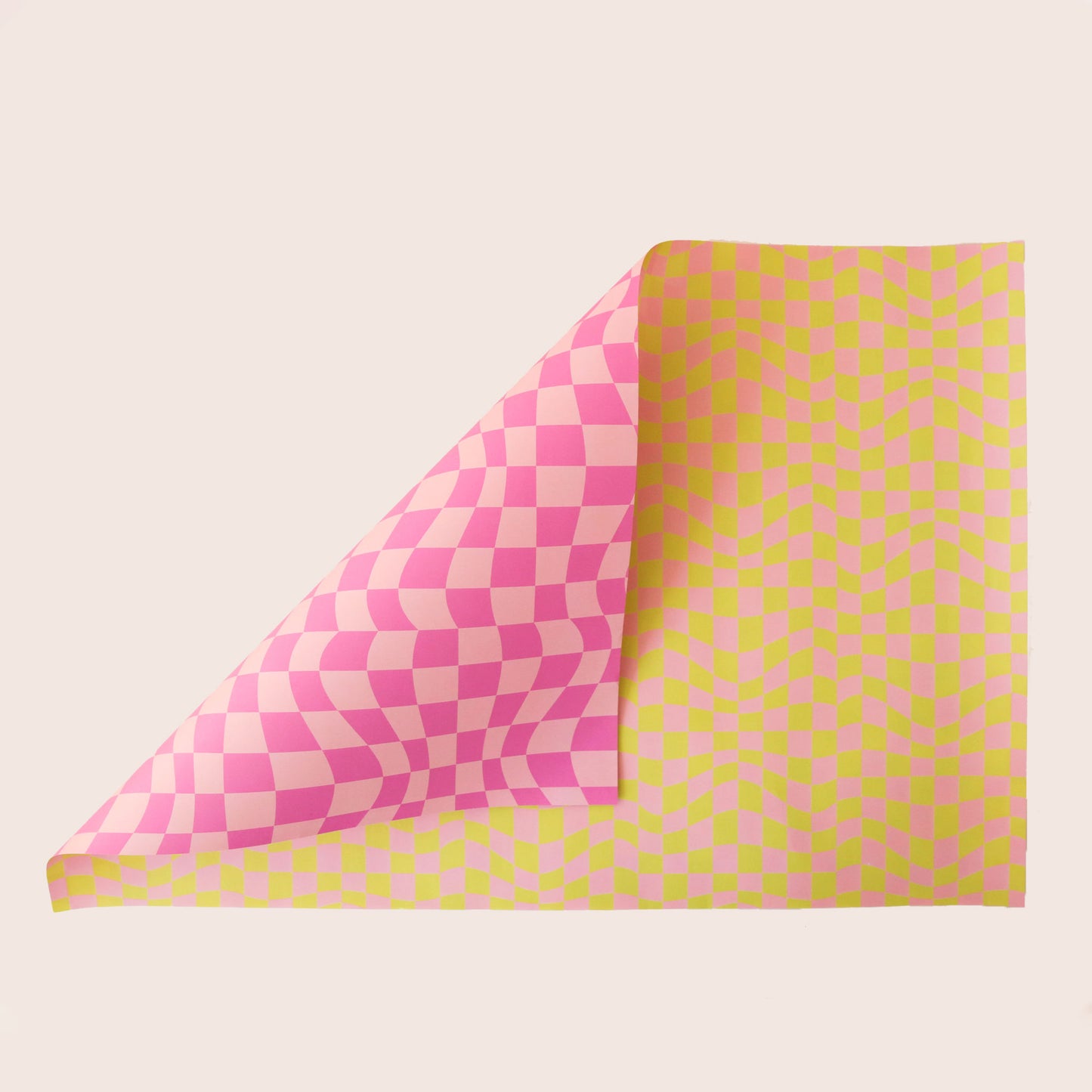 Sheet of distorted pink and yellow checkered wrapping paper. The sheet is bent forward, revealing the other side of the wrapping paper. The back side is covered in distorted pink checkered print.