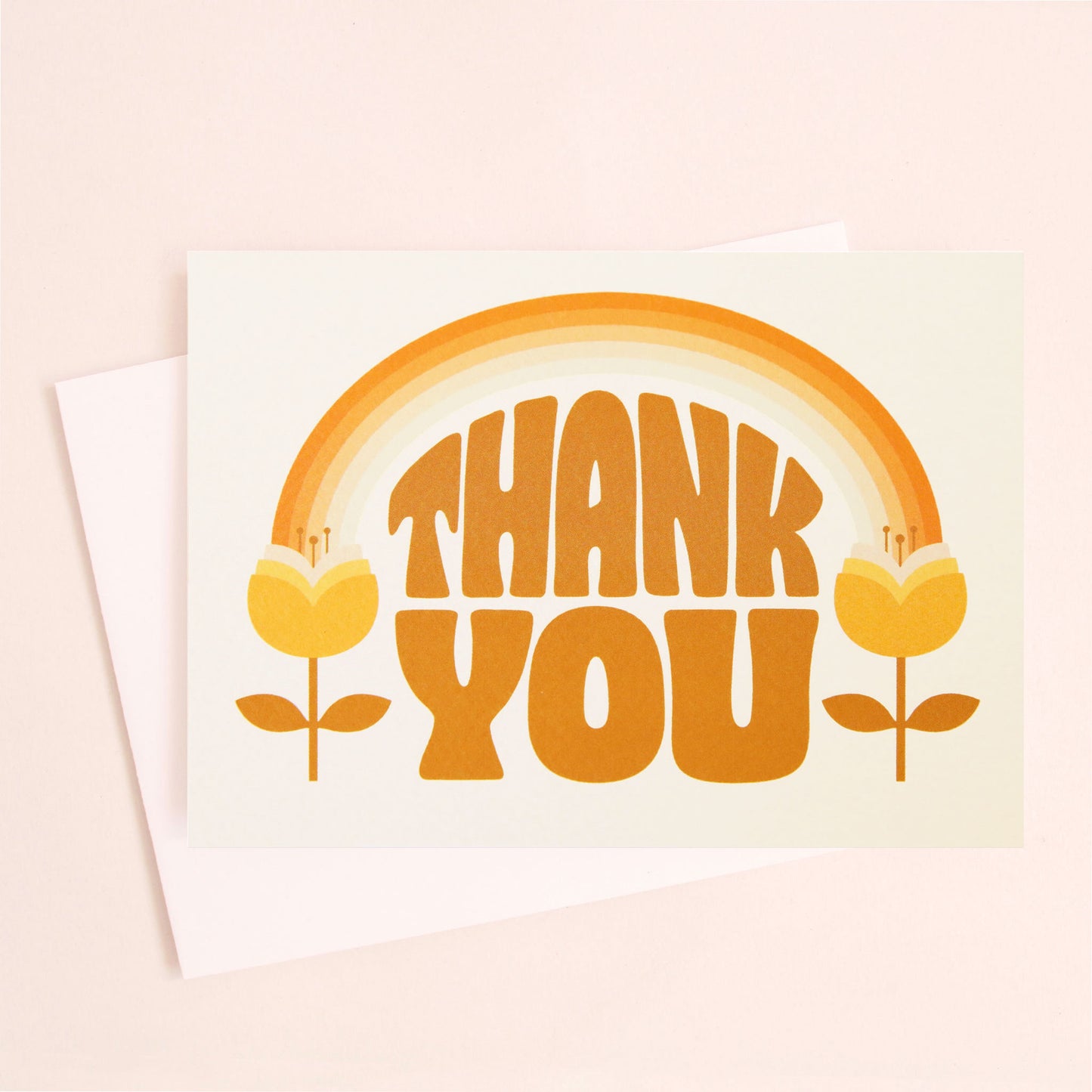 A white card and white envelope with orange 70's text that reads, "Thank You". The illustration on the card is an orange toned rainbow feeding into two tulip flowers on either side.