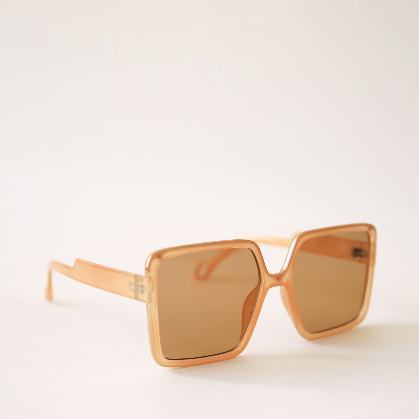 70's inspired square sunglasses with an oversized tan frame and tannish / orange lenses.