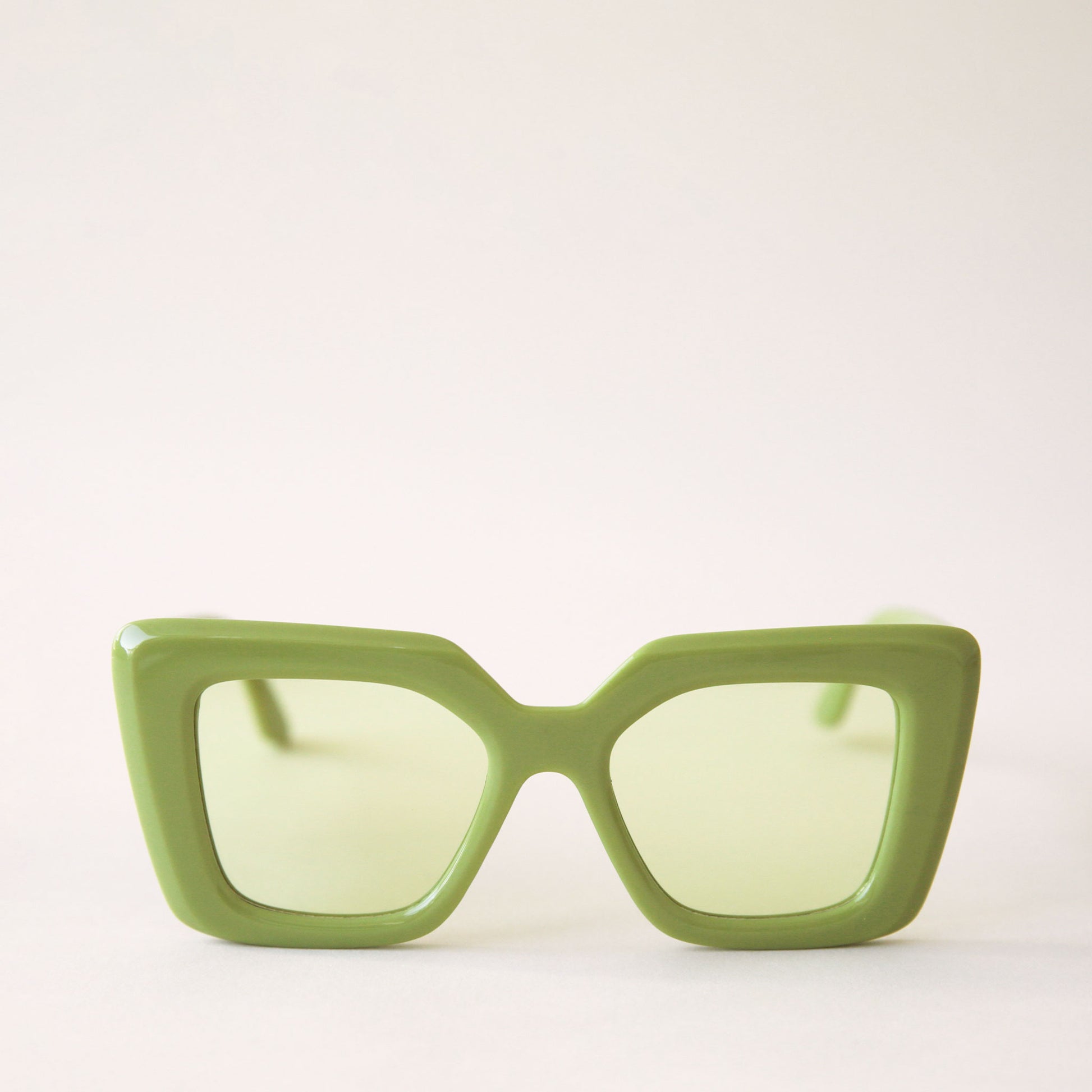 70's inspired sunglasses with a lime green, rectangle frame that has a slight cat eye point at the tops along with light green lenses.