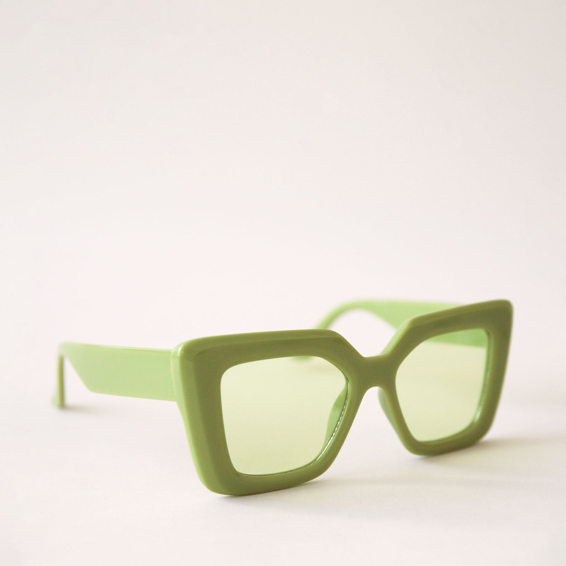 70's inspired sunglasses with a lime green, rectangle frame that has a slight cat eye point at the tops along with light green lenses.