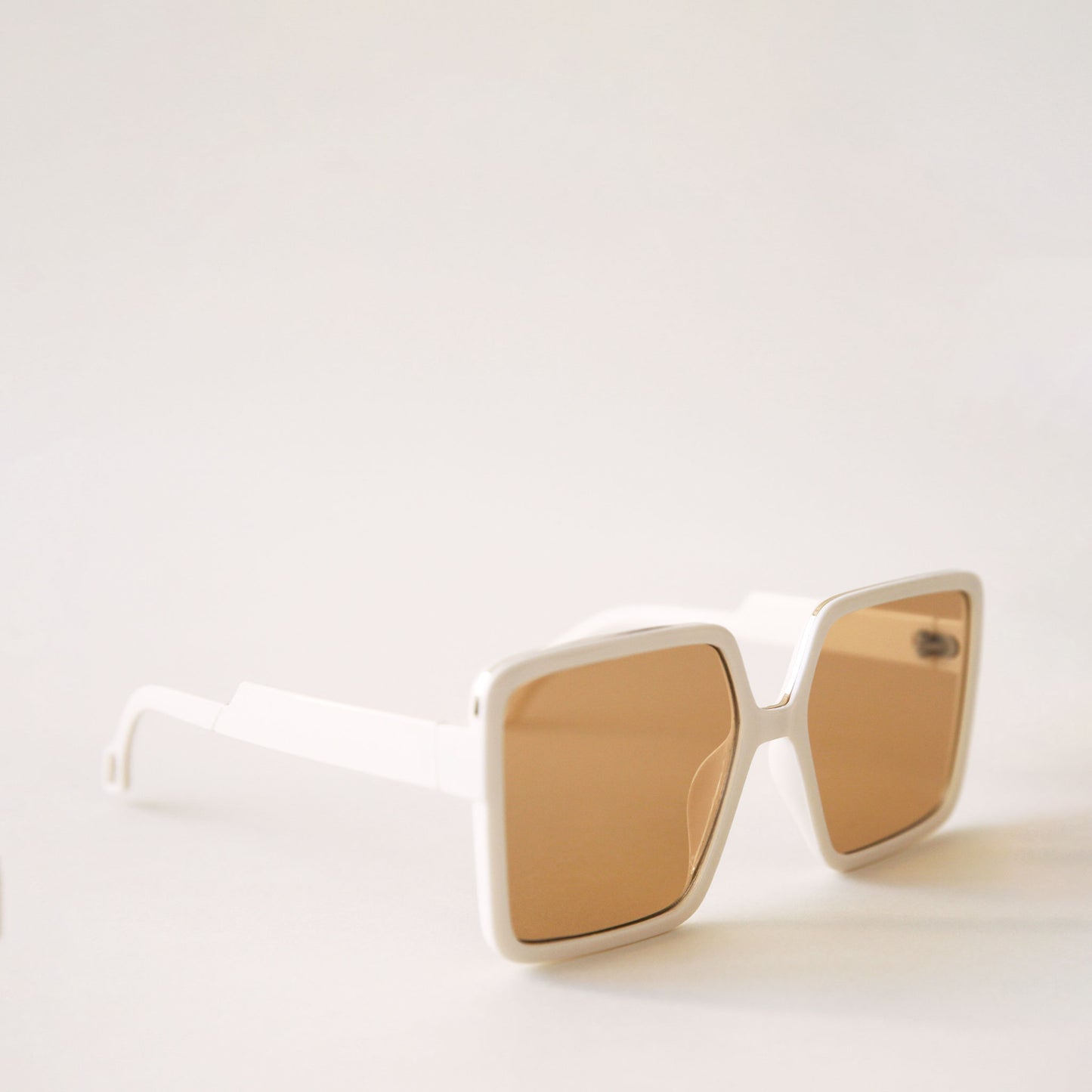 70's inspired square sunglasses with an oversized white frame and amber colored lenses.