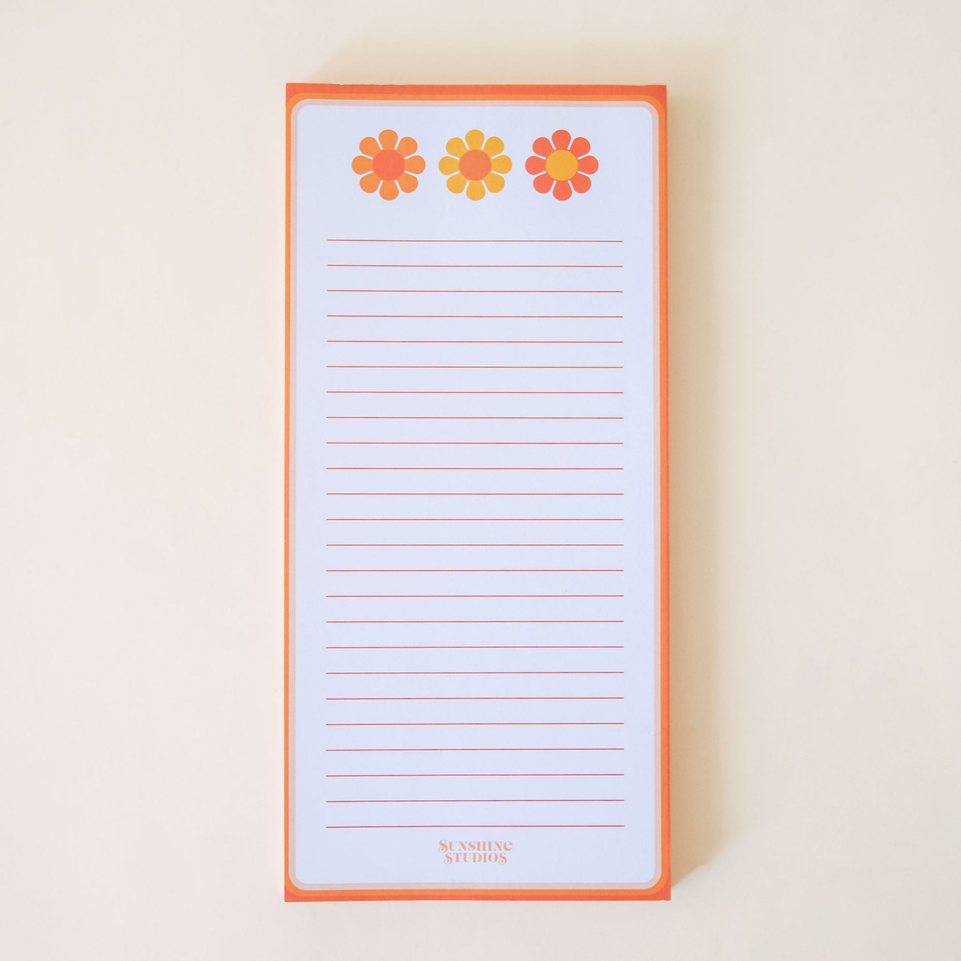 Classic rectangular notepad filled with orange lines perfect for note taking. The notepad is bordered with neon orange tones. Above the lines sits a row of three warm yellow and orange flowers. The bottom of the pad reads 'Sunshine Studios'.
