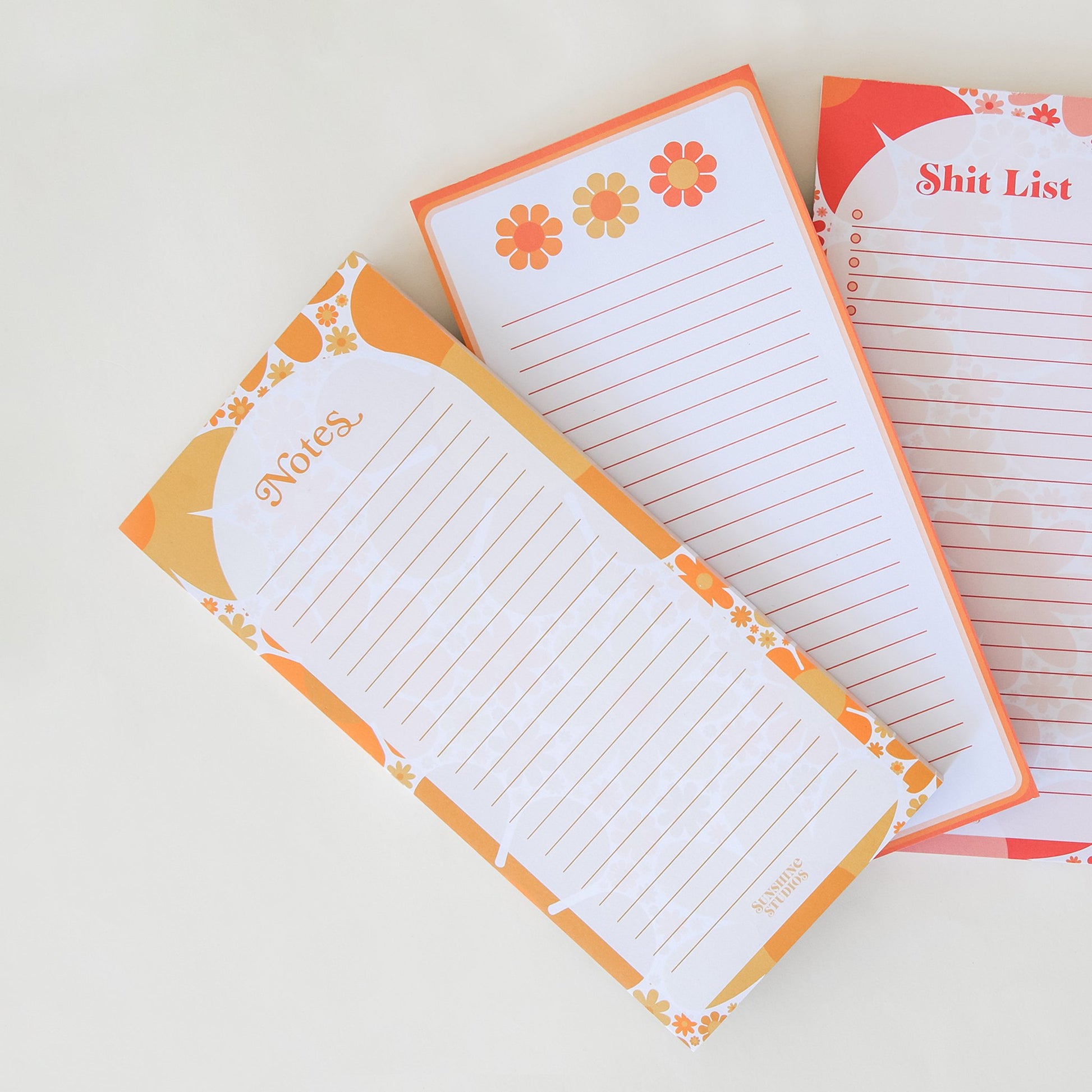 Three notepads filled with lines perfect for note taking. Each notepad infilled with retro inspired orange, yellow and red designed borders. The notepads each have their own design. The left notepad is labeled 'Notes' and the right is labeled 'Shit List'.