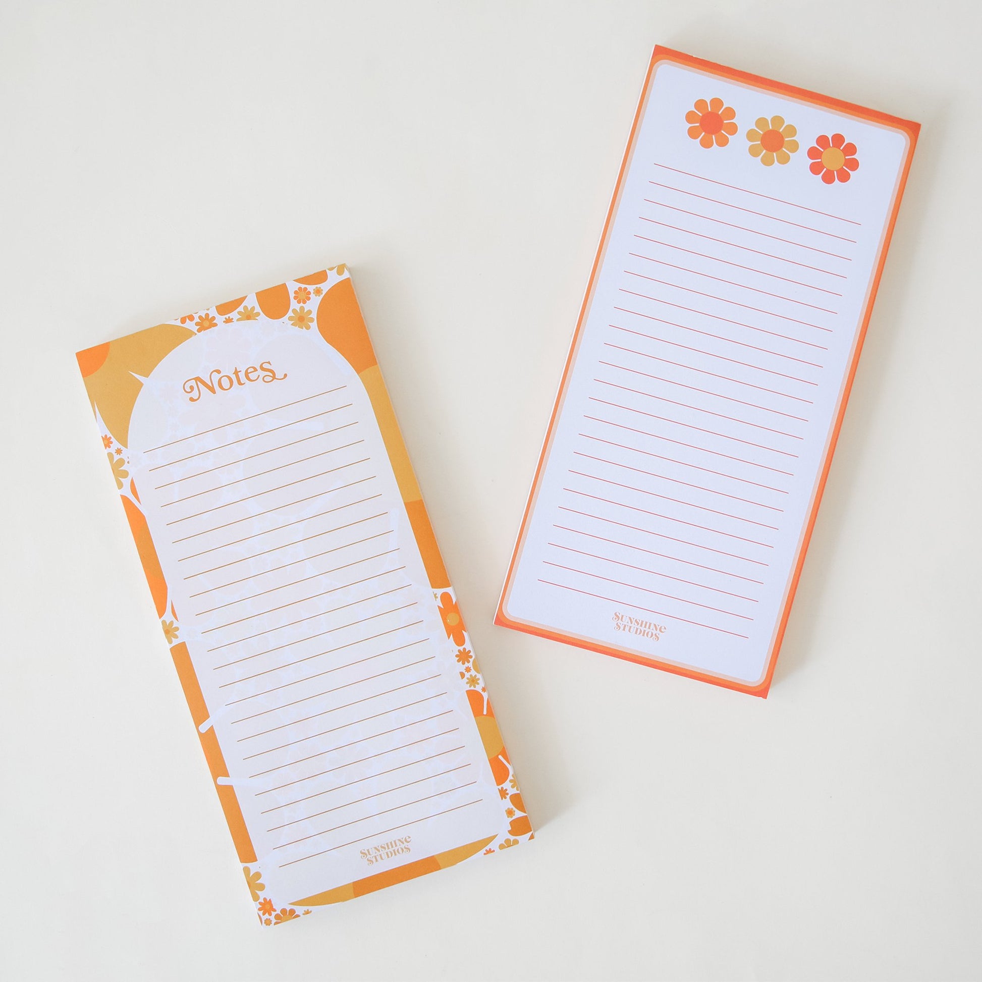 Two notepads filled with lines perfect for note taking. Each notepad infilled with retro inspired orange, yellow and red designed borders. The notepads each have their own design. The left notepad is labeled 'Notes' and the right has three warm toned flowers above the lines.