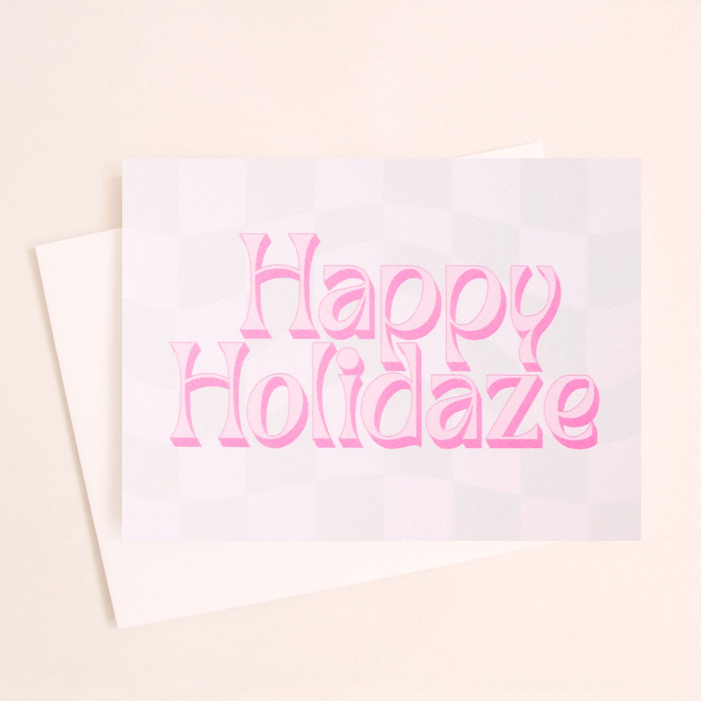 Pale mint and cream checkered card that reads 'Happy Holiday' in retro pink lettering with thin magenta shadow. The card is accompanied by a solid white envelope. 