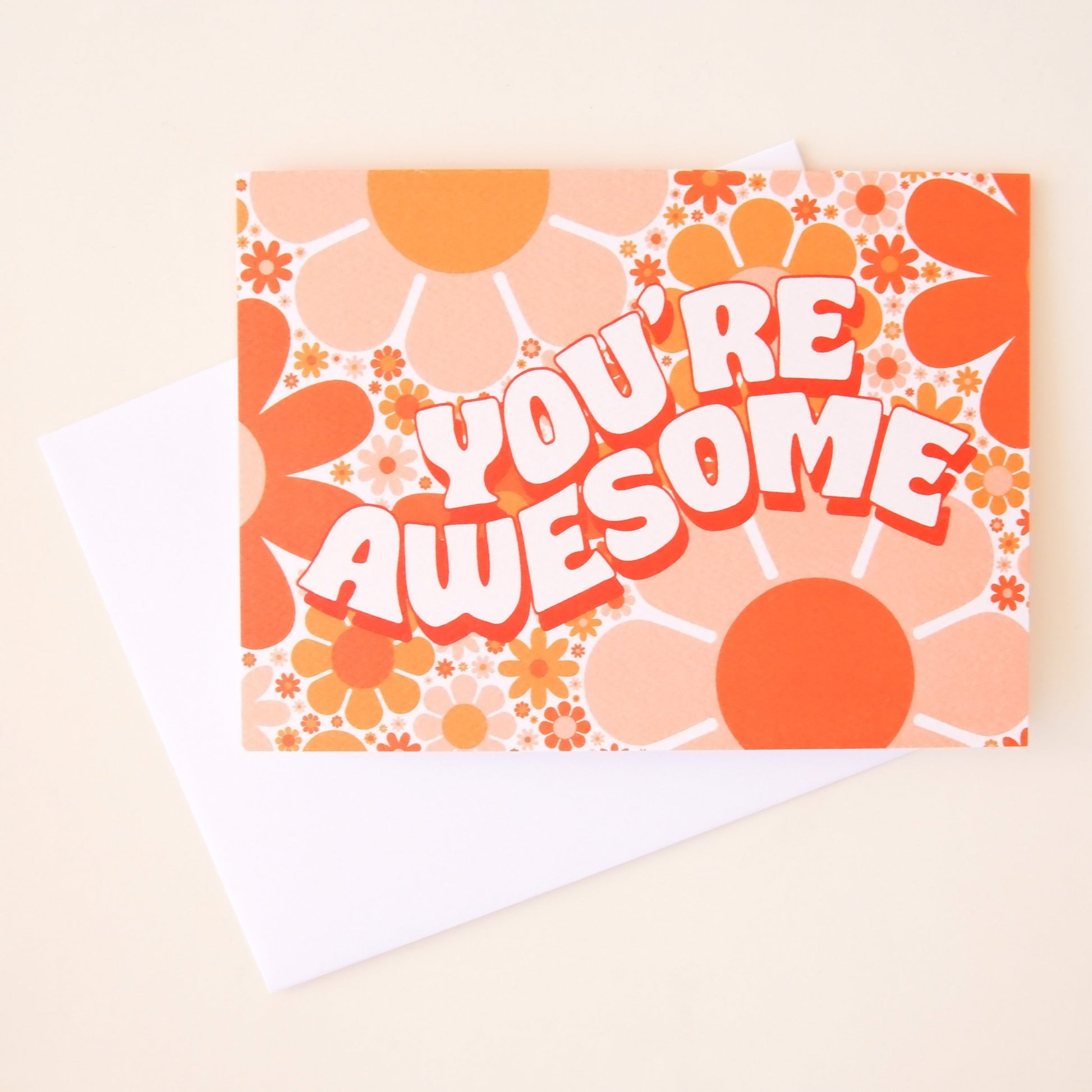 Card filled with orange and pink retro flower design. The car dreads 'you're awesome' in white curved bubble lettering with tangerine orange shadow detailing.