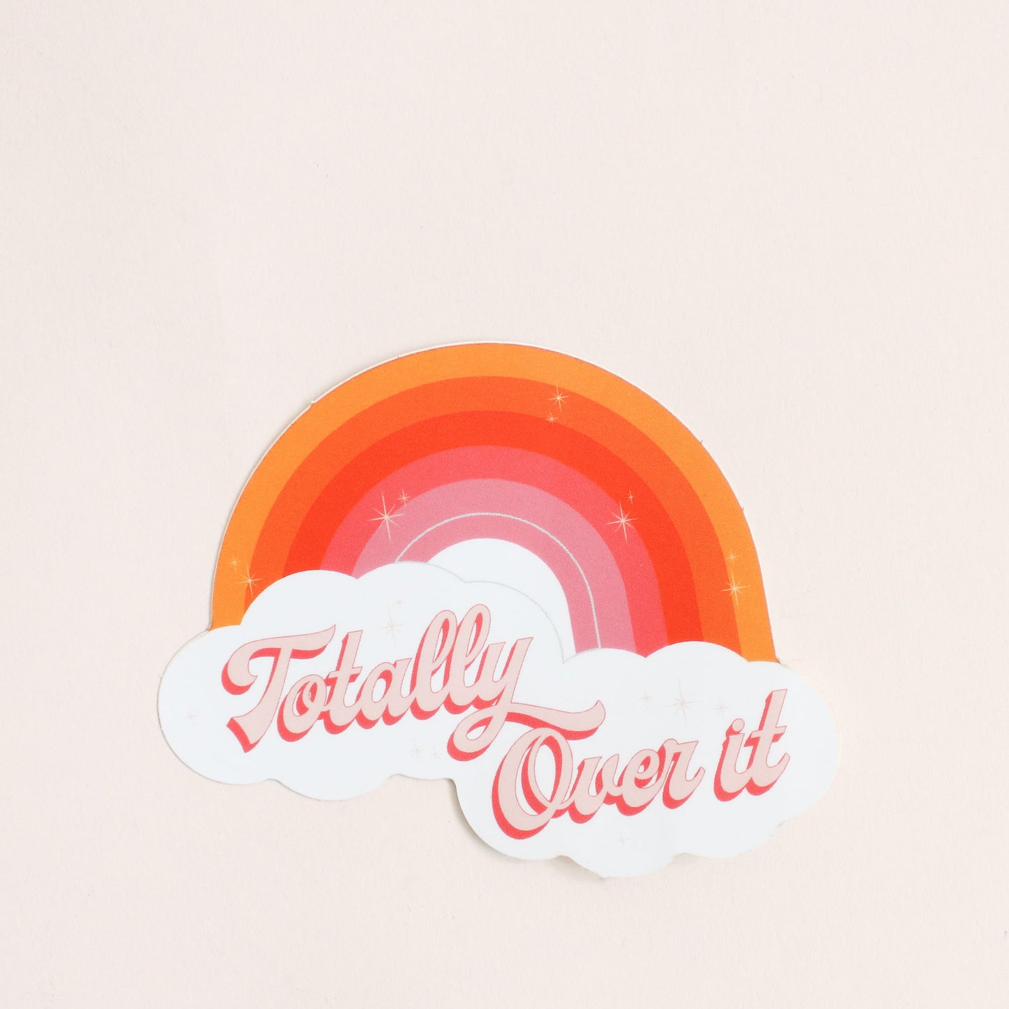 Bright rainbow designed sticker with orange sunset hues. This sticker reads 'Totally Over It' in pink cursive lettering below the rainbow in white clouds. 