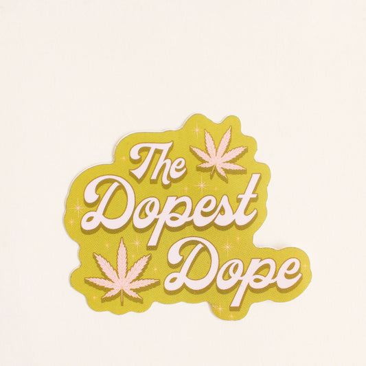 This olive green sticker reads 'The Dopest Dope' in pastel pink surrounded by two pink marijuana leaves and twinkling detailing. 