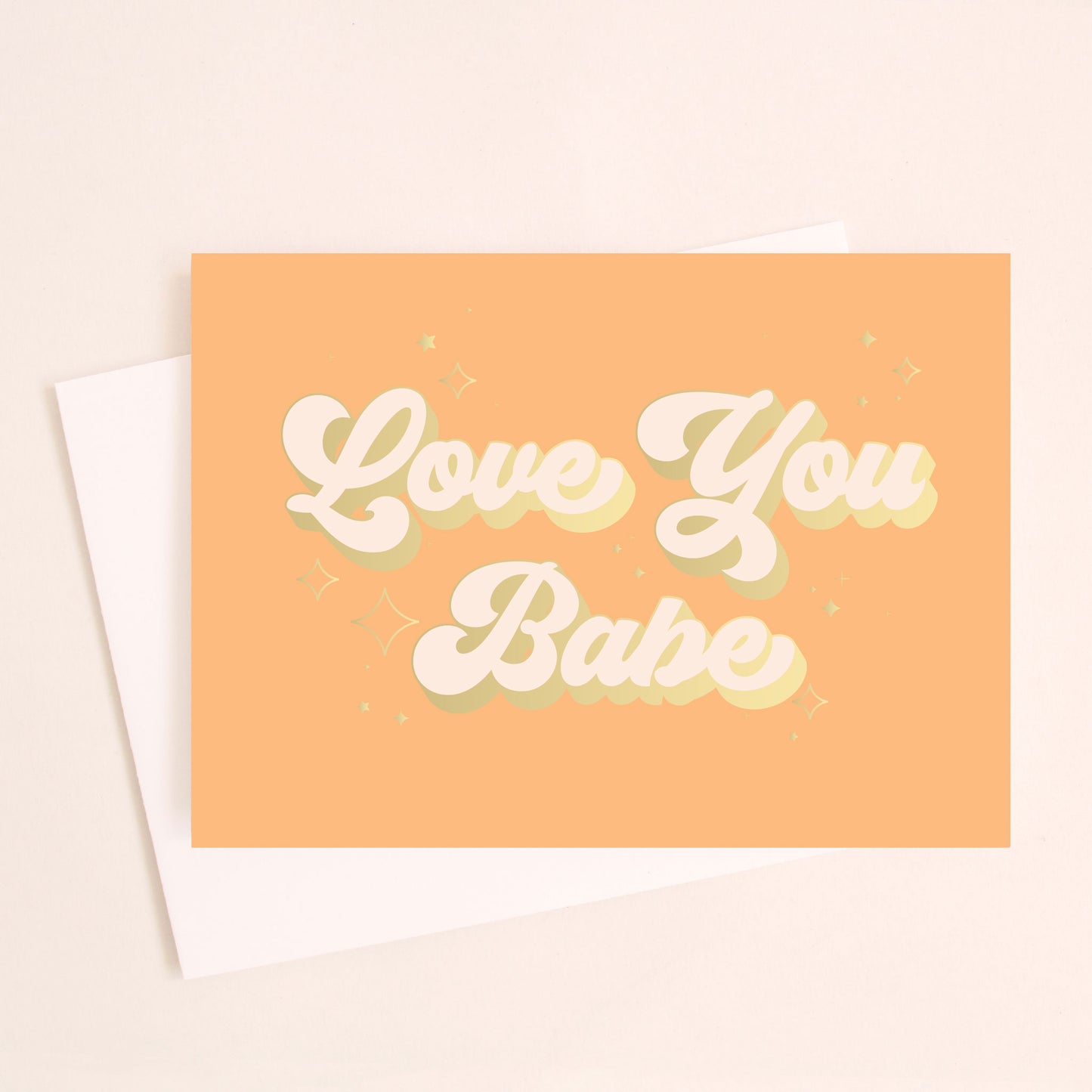A tangerine greeting card with cursive bubble font that reads, "Love You Babe" in cream text and detailed with a gold border around the letters as well as golf foiled sparkle graphics around the words.