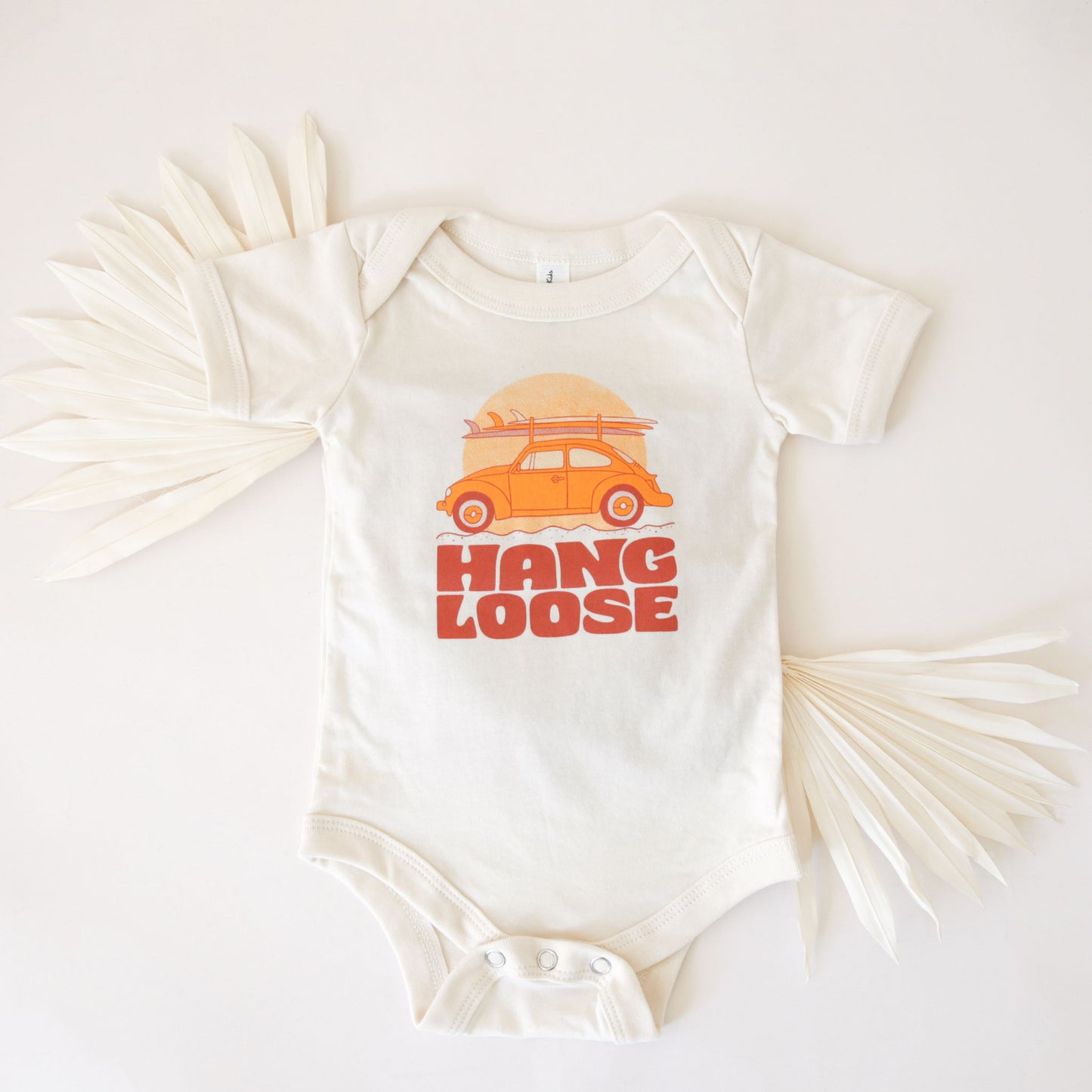 A white cotton onesie with the sweetest VW bug with surfboards and the text, "Hang Loose" burnt orange font.